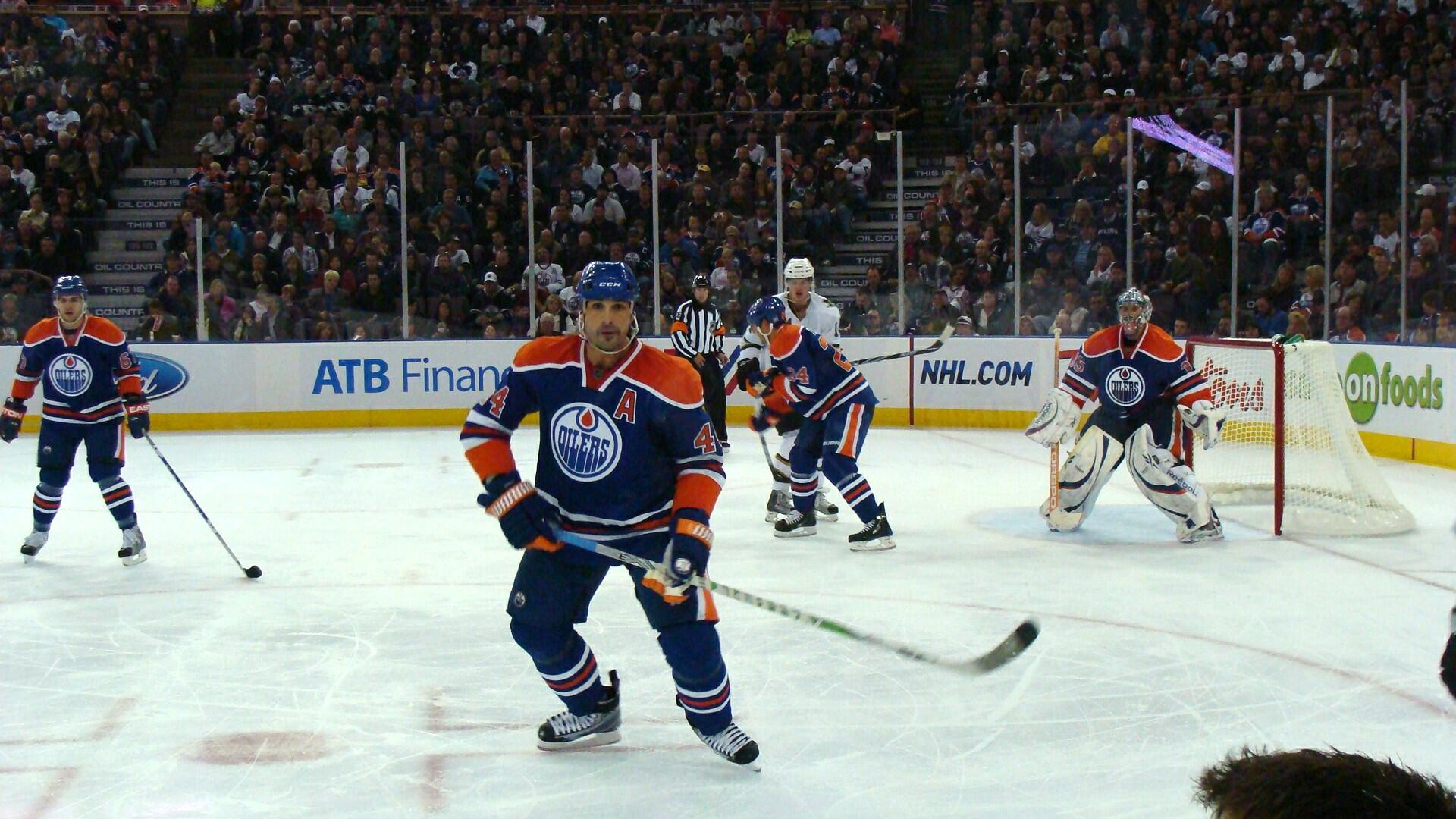 Det kanadensiska ishockeylaget Edmonton Oilers spelar en match på isen. Arenan är fullsatt med publik.