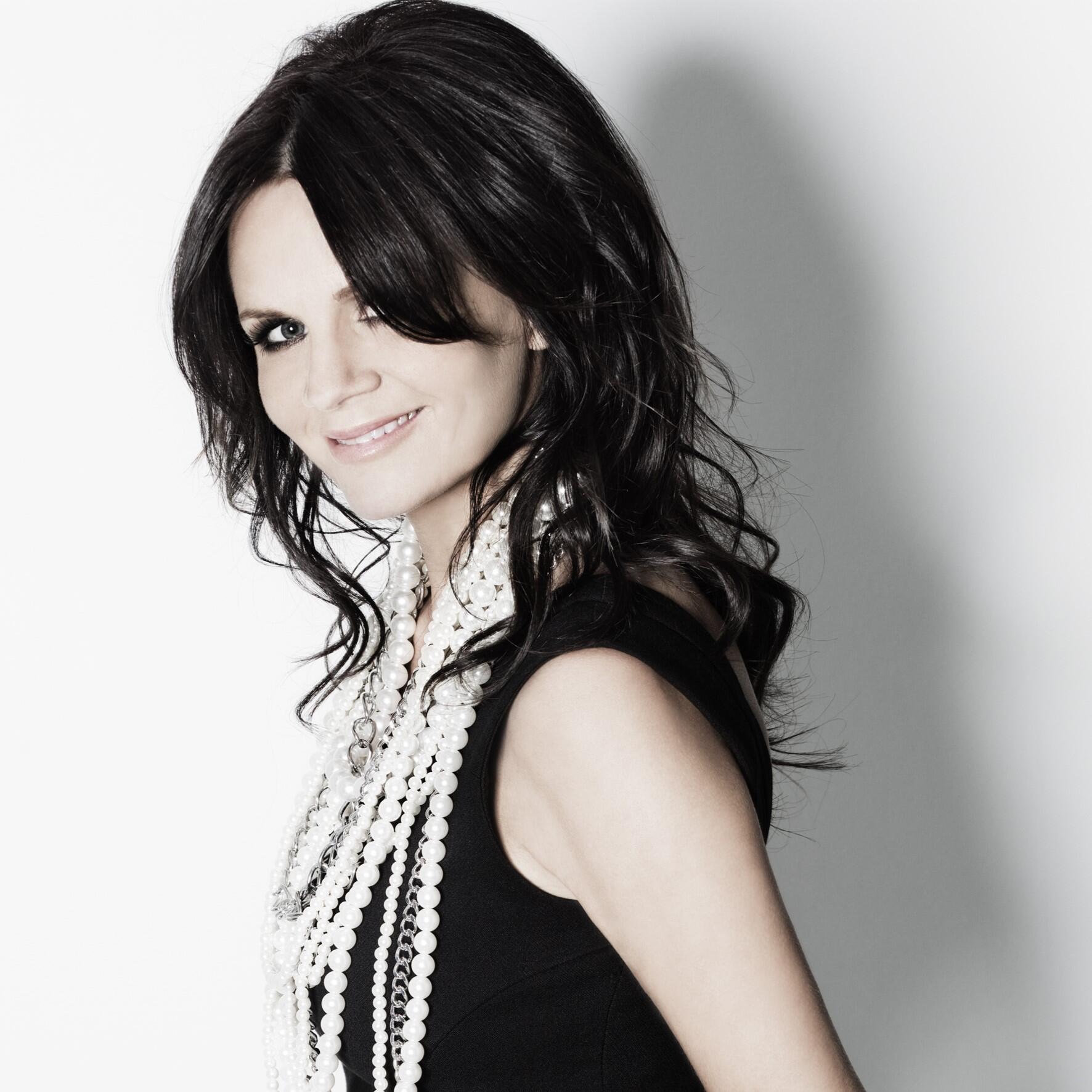 Lena Philipsson poserar mot en slät vit bakgrund och tittar rakt in i kameran.