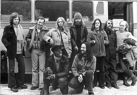 Svartvit bild på musikgruppen Kebnekajse från 70-talet. Bandet på 8 personer poserar framför sin turnebuss.