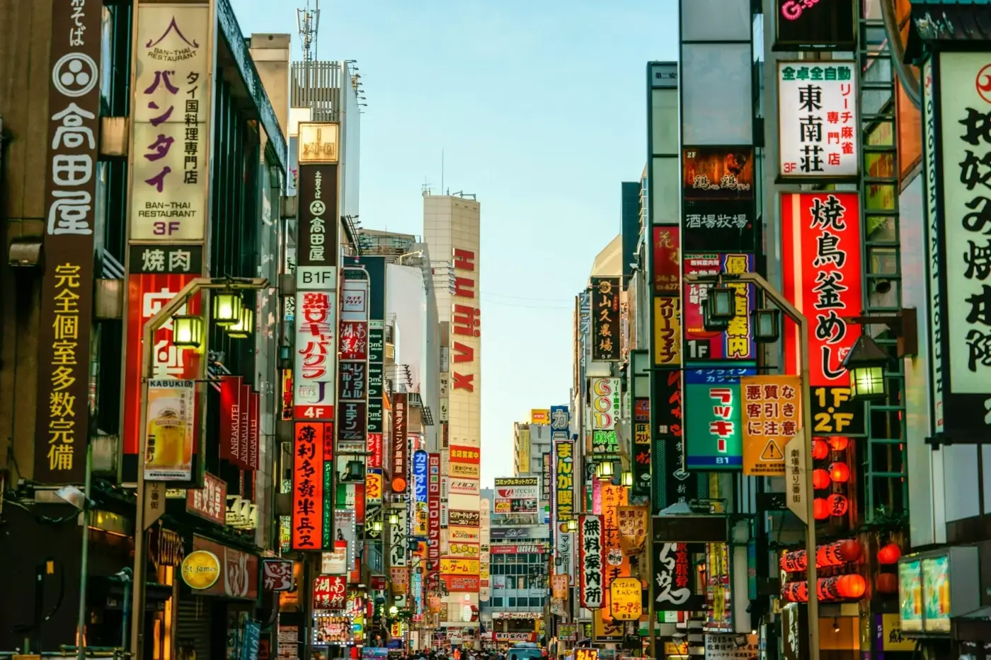 Fartfylld gata i en japansk storstad. I bilden syns fullt med skyltar i neon.