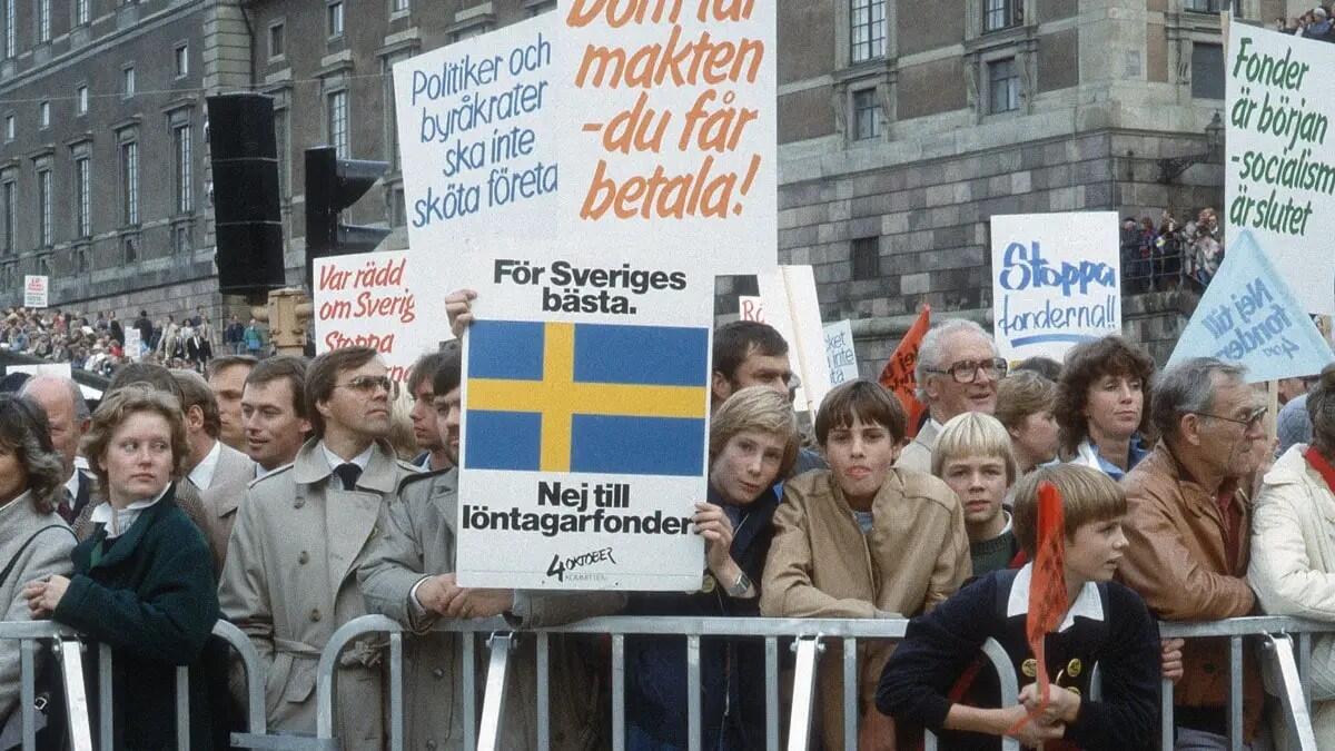 En samling demonstranter står med skyltar utanför slottet i Stockholm och protesterar 1983.