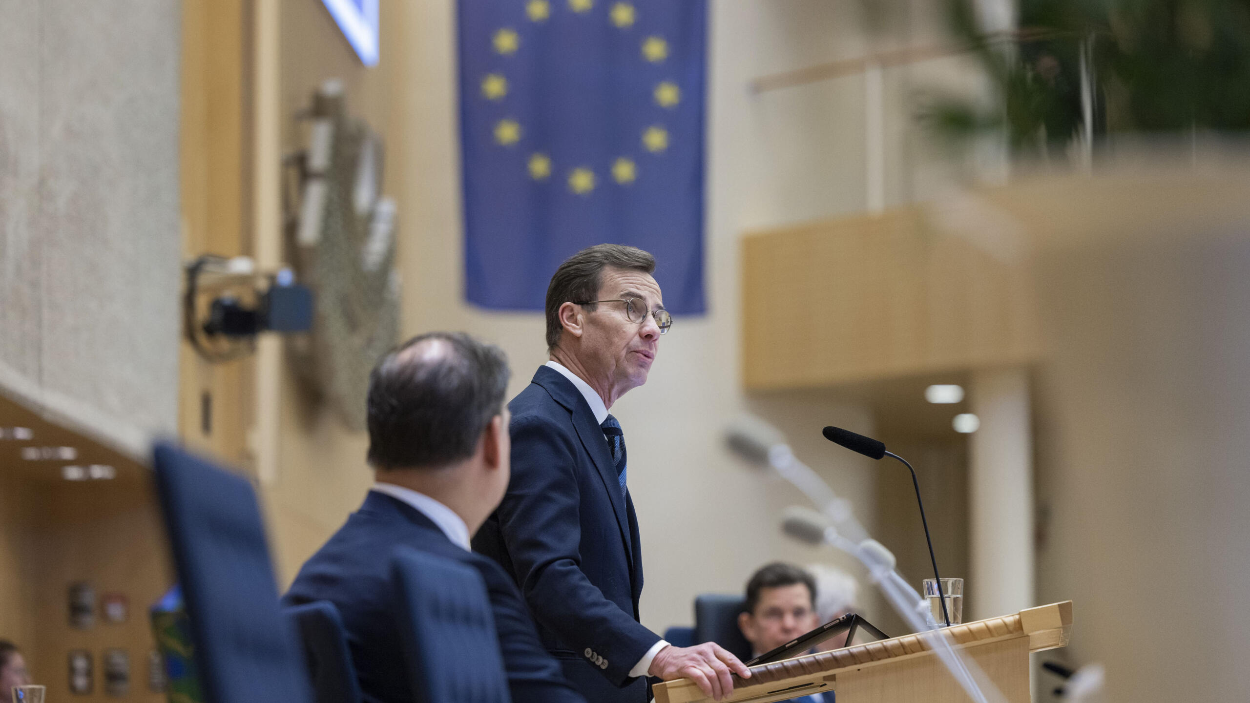 Ulf Kristersson, nuvarande stadsminister, står i talarstolen och pratar inför svenska riksdagen.