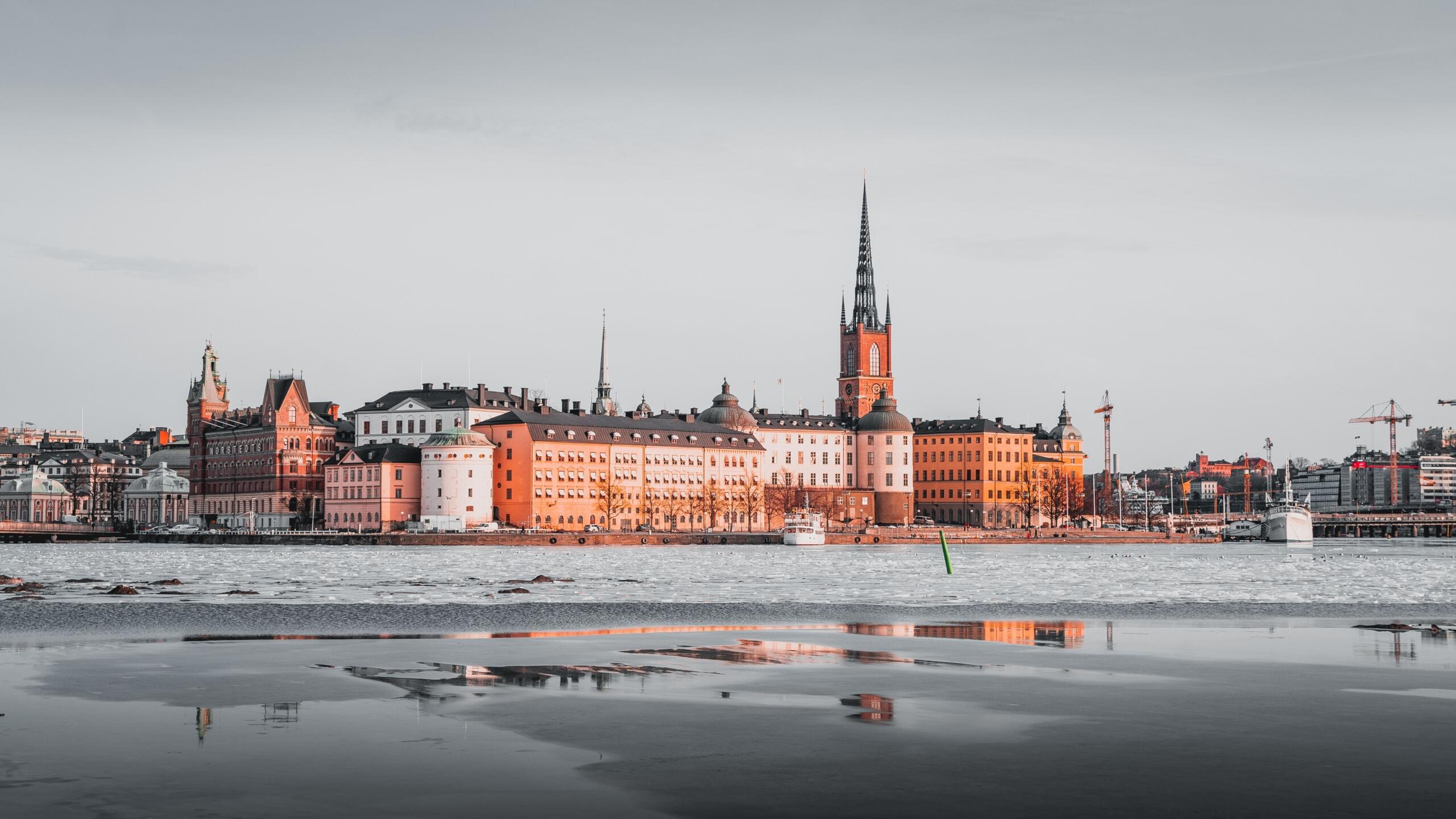 Vy över Stockholms bebyggelse och Riddarholmskyrkans höga spira, sedd över vattnet.