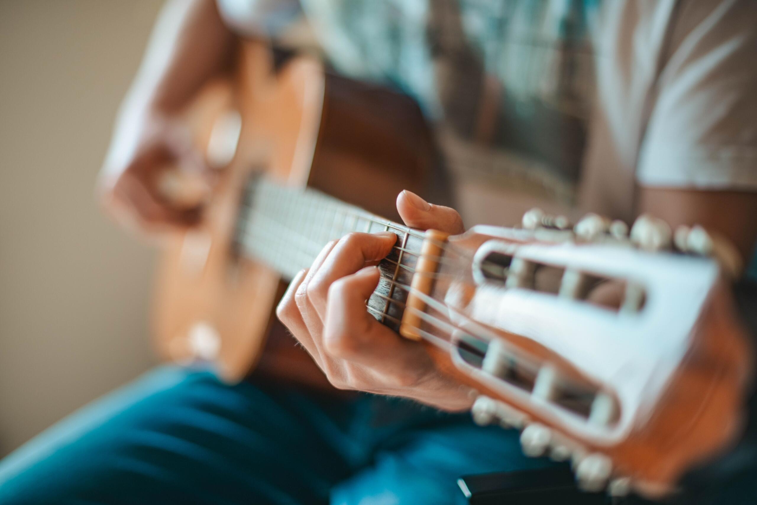 Närbild av en person som håller ett ackord på en akustisk gitarr.