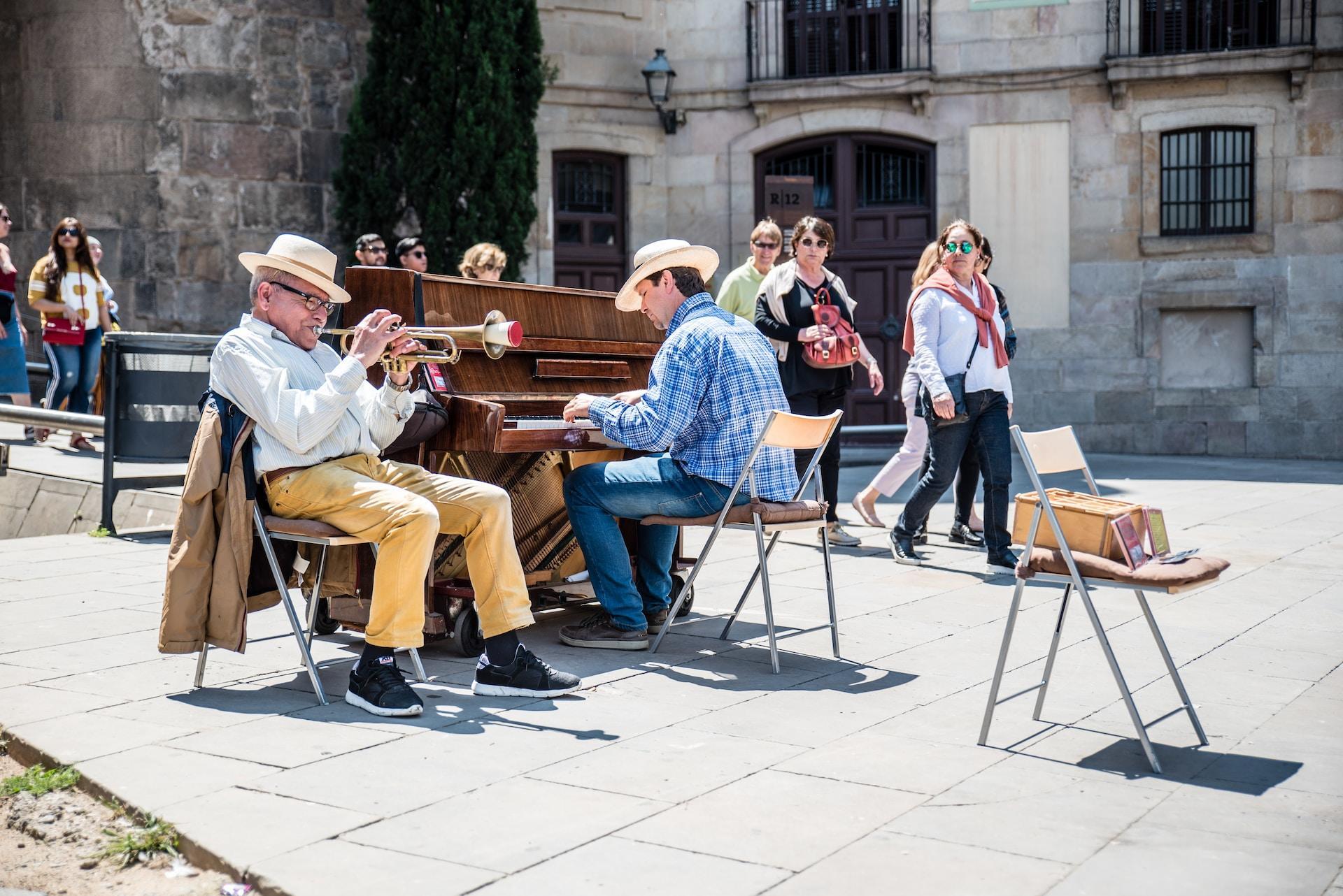 En pianist och en trumpetare spelar tillsammans utomhus framför förbipasserande.