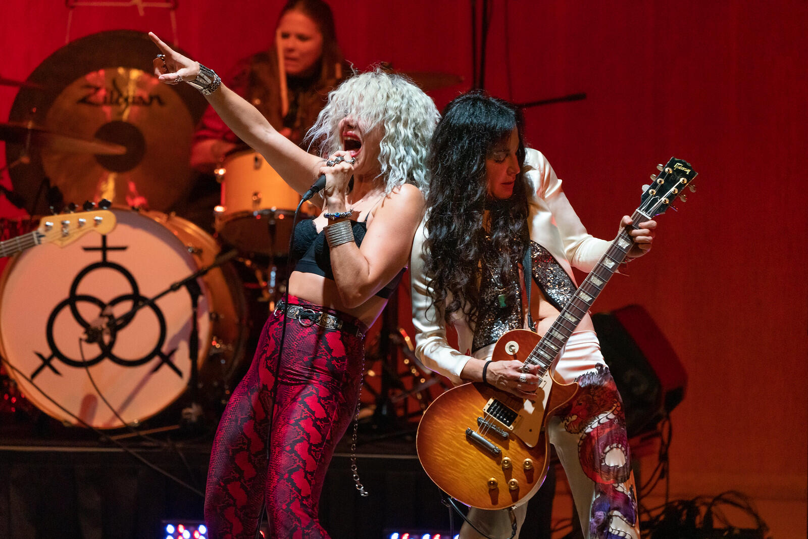 Two women on stage: one is playing the guitar and another is singing. 