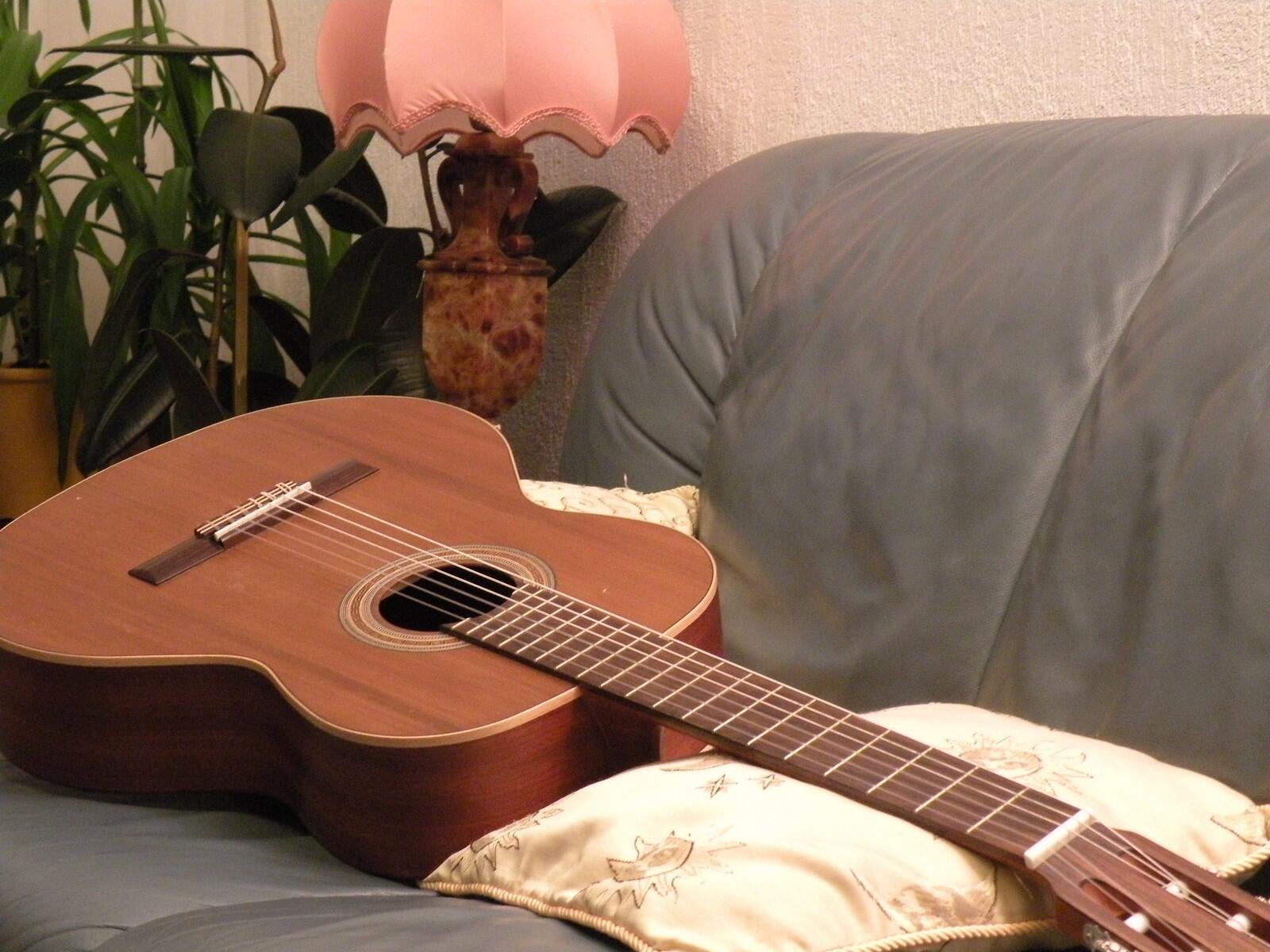A brown acoustic guitar on the sofa. 