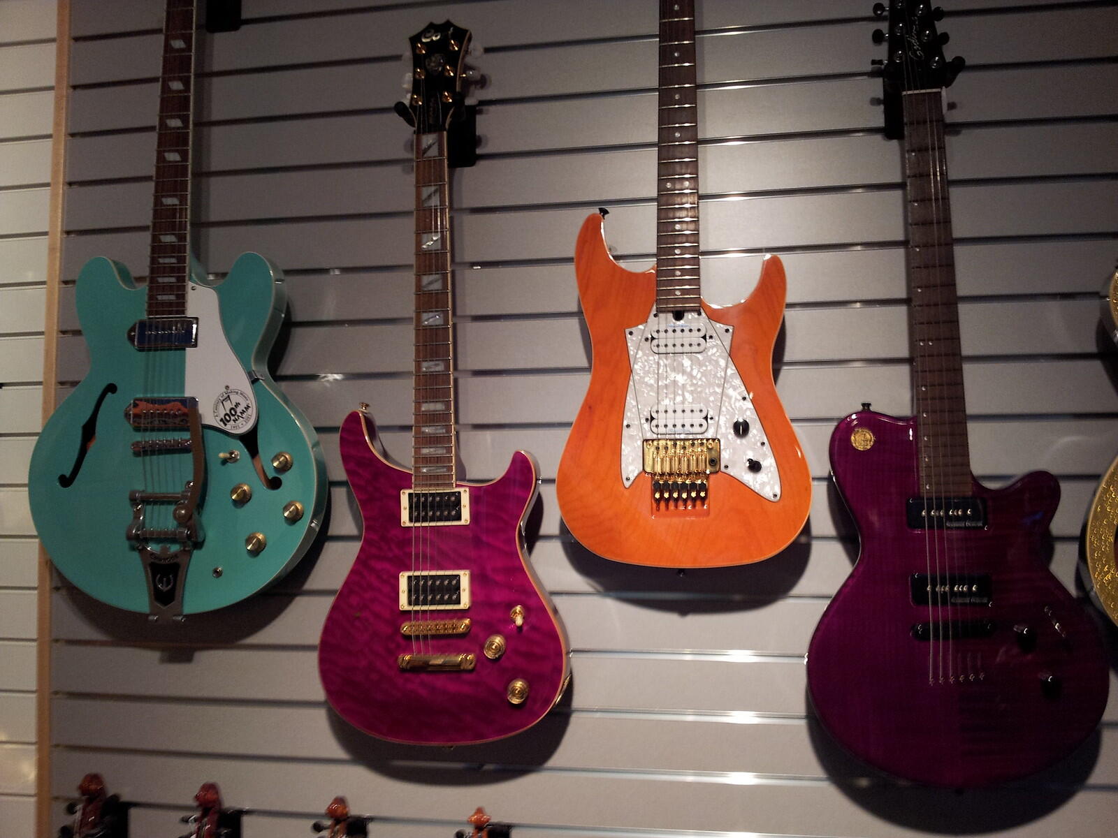 Electric guitars in different colours hanging on the wall.