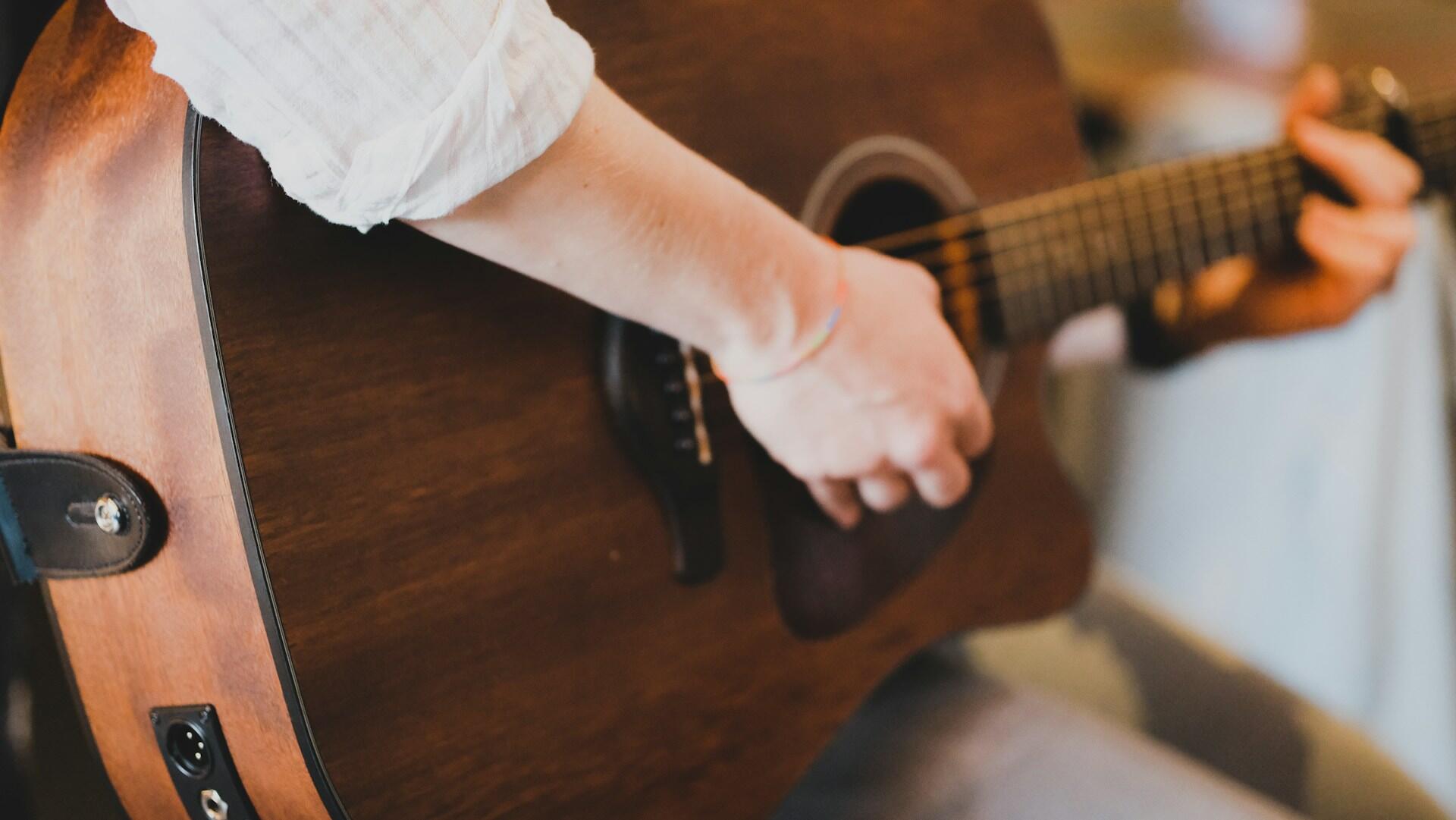A person strumming on what it seems to be an acoustic guitar. 