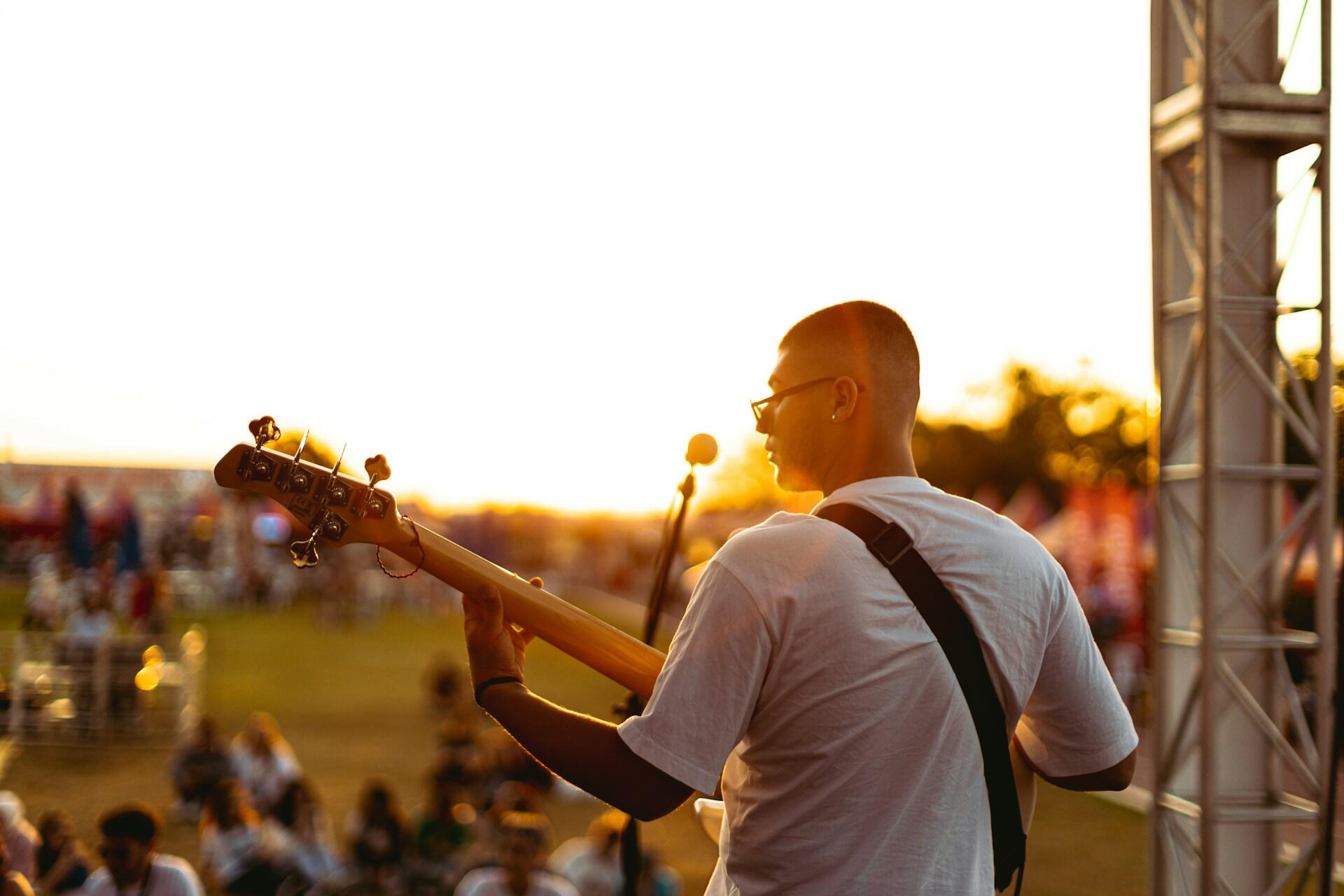 A man holding a guitar and performing in front of a crowd. 