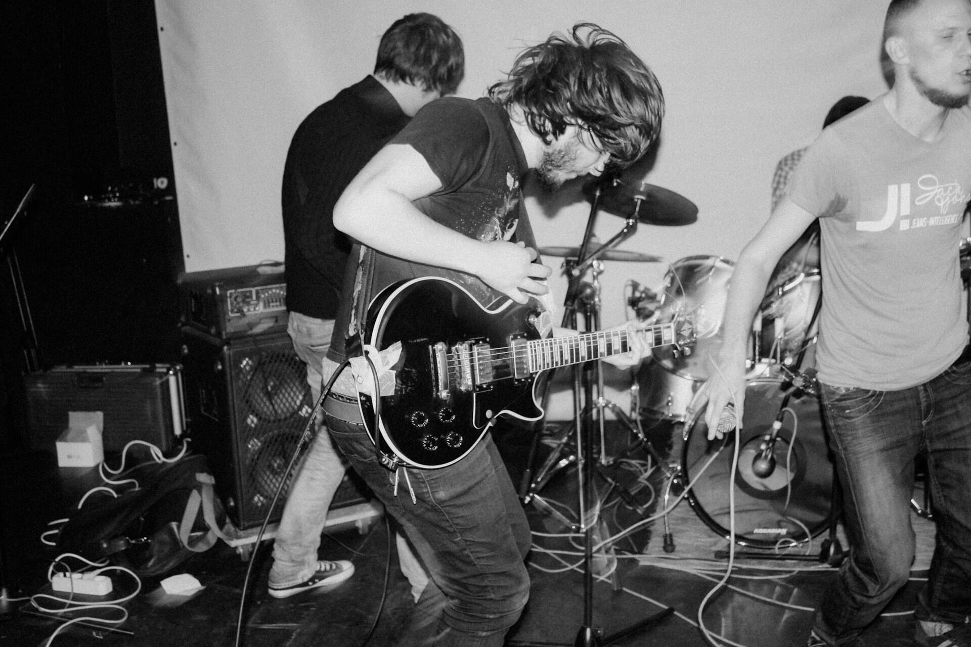 A man playing guitar beside woman in black t-shirt.