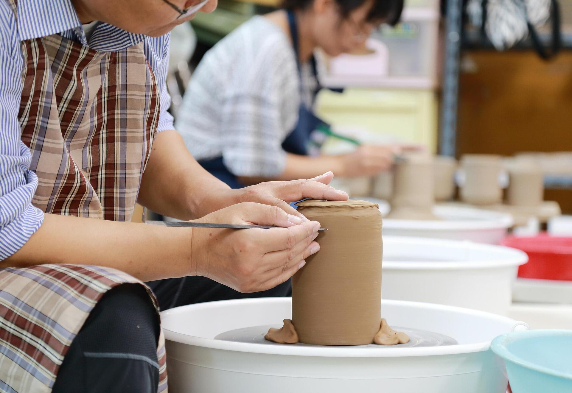 A young child shaping a small clay pot on a pottery wheel