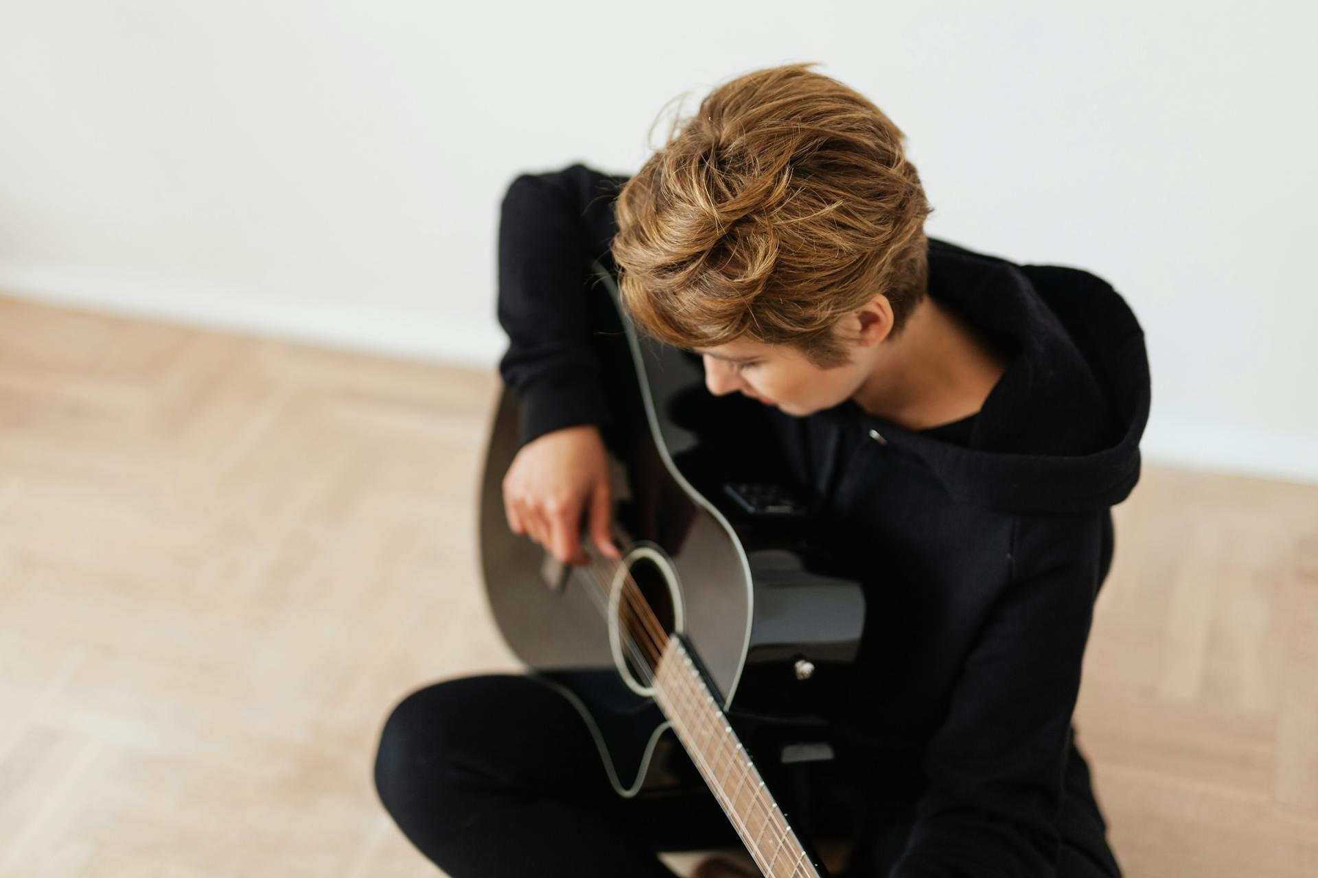 Person in Black Hoodie Playing Acoustic Guitar