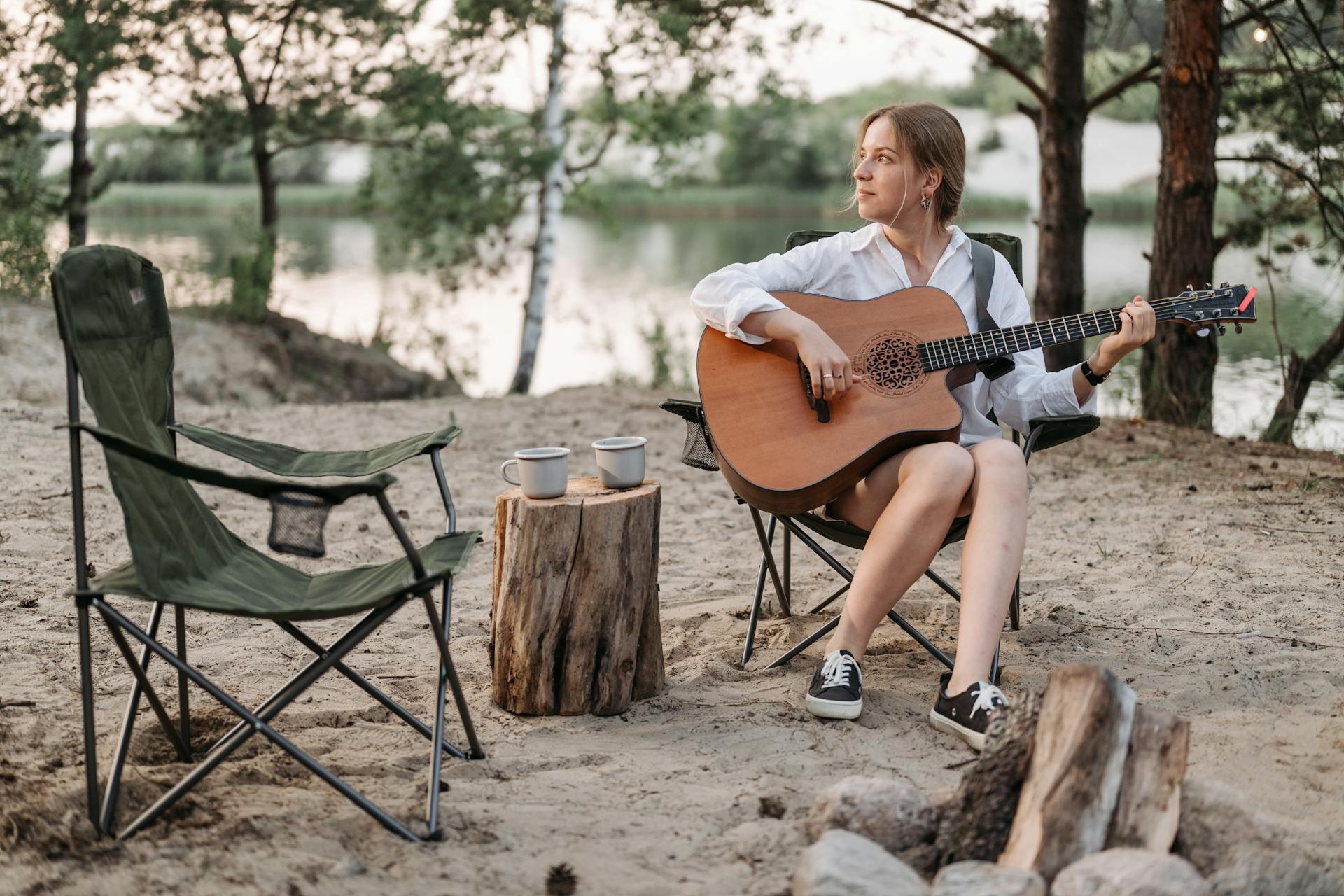 A Woman Sitting on a Chair Playing Acoustic Guitar