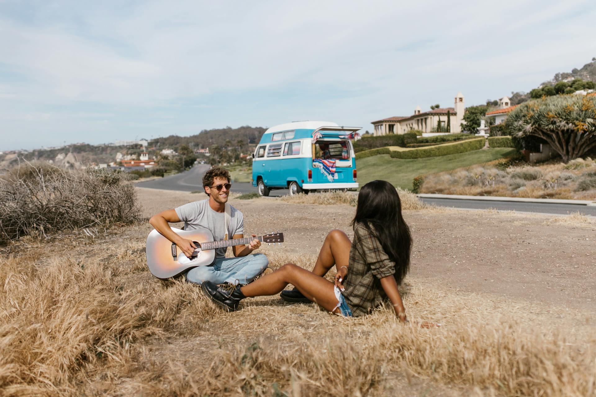 A Couple Sitting on a Roadside playing the guitar. 
