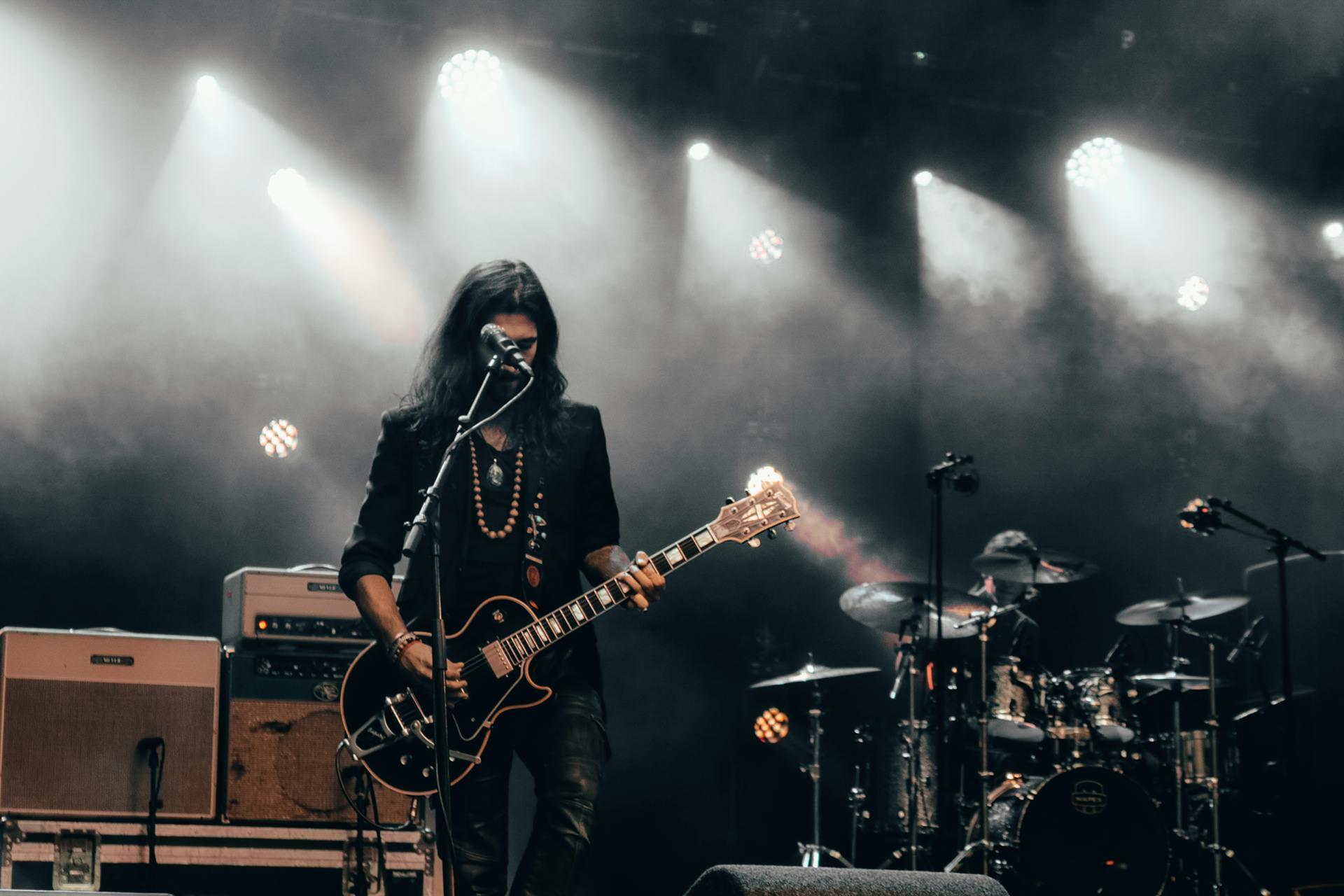 Man Playing Guitar While Standing Near Microphone.