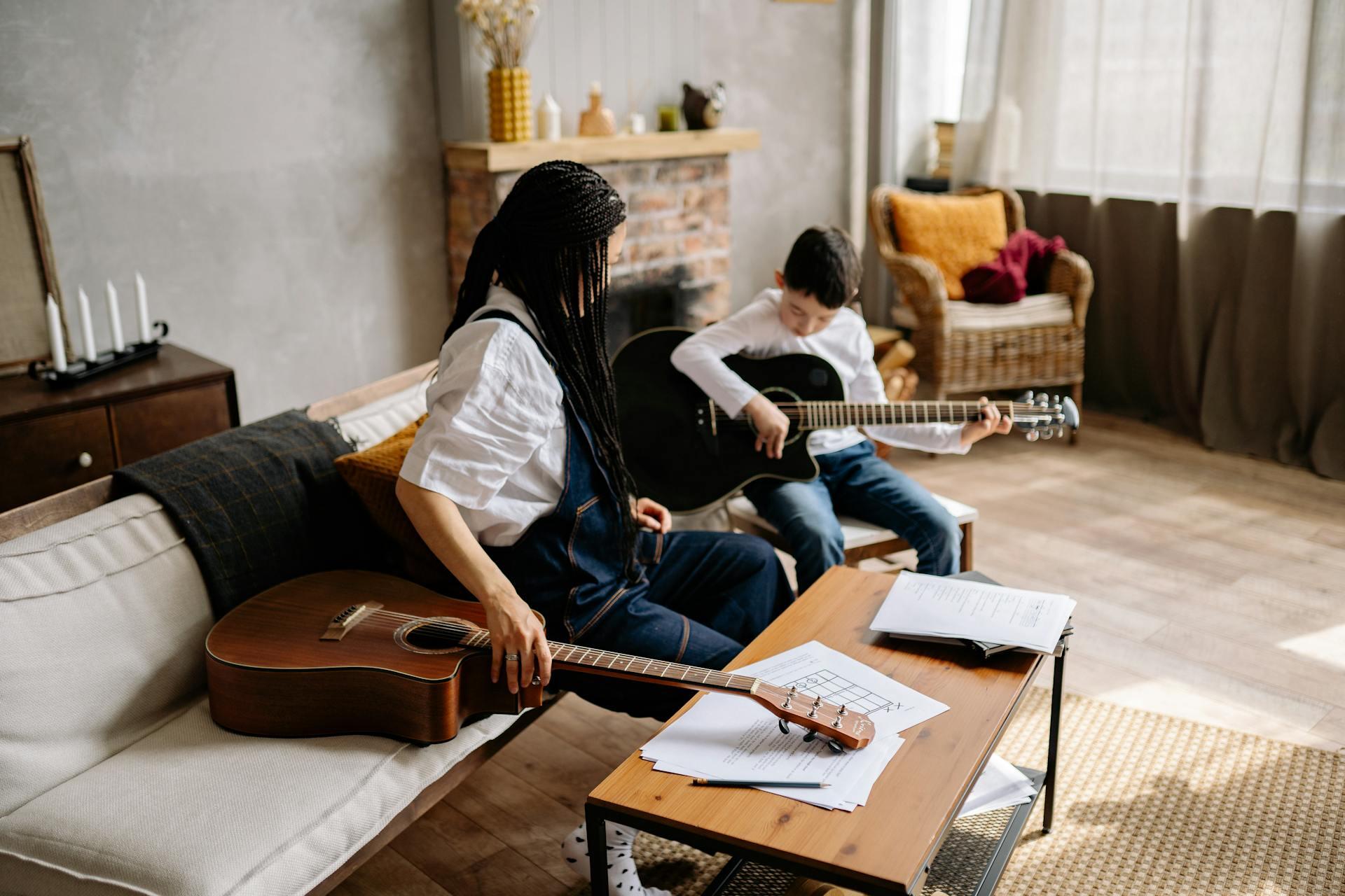Woman and child sitting on a couch playing a classical string instrument together.