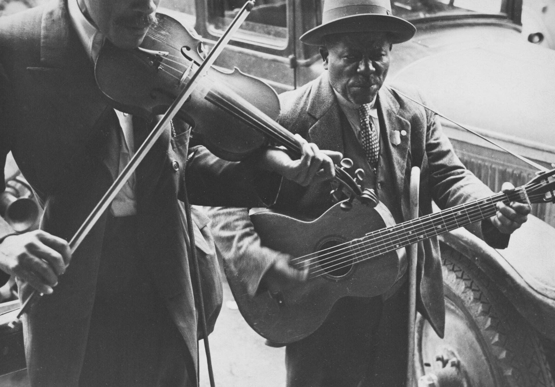 Musicians with upright bass and guitar in vintage black and white photo.