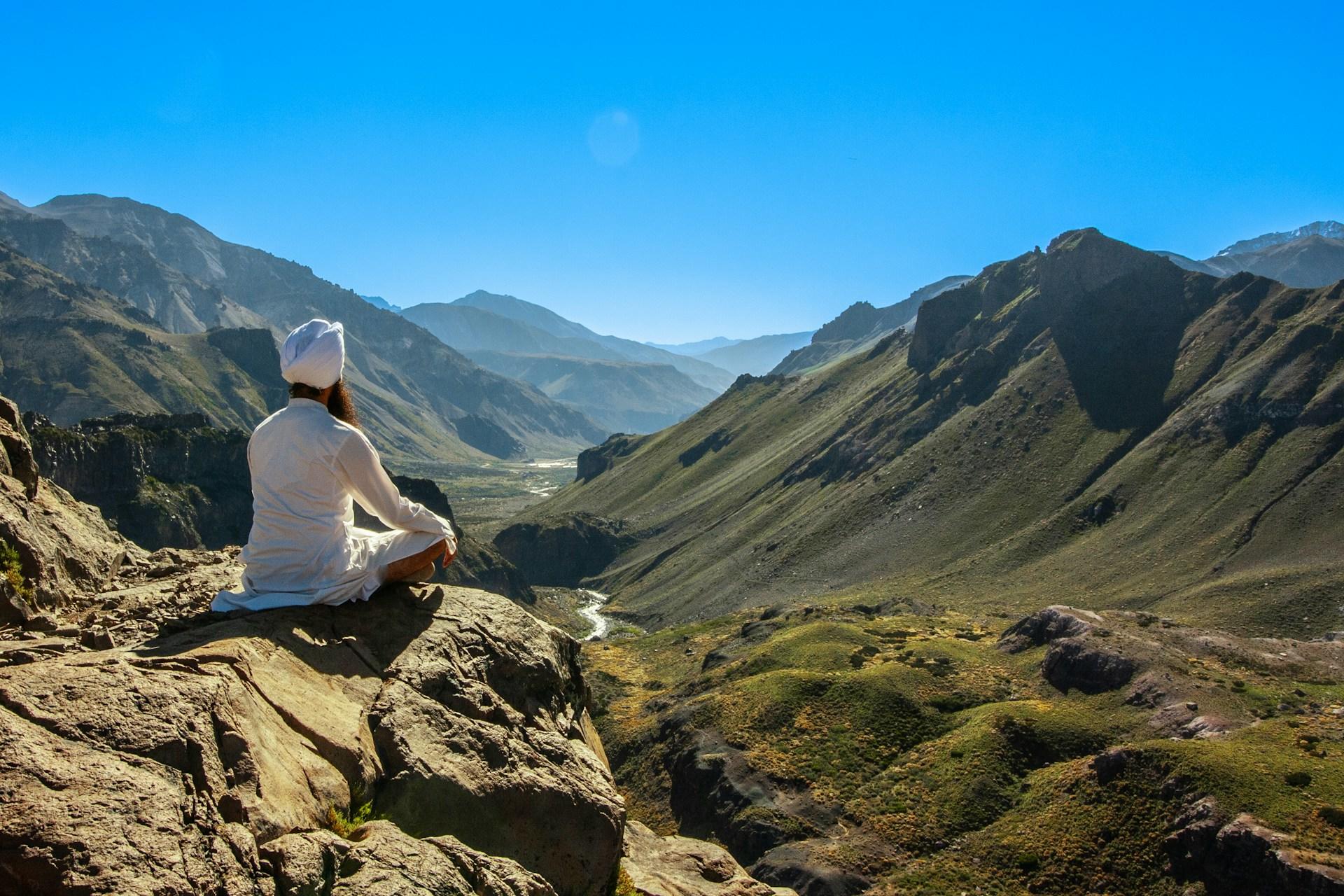 A Kundalini yogi wearing all white and sitting on a cliff