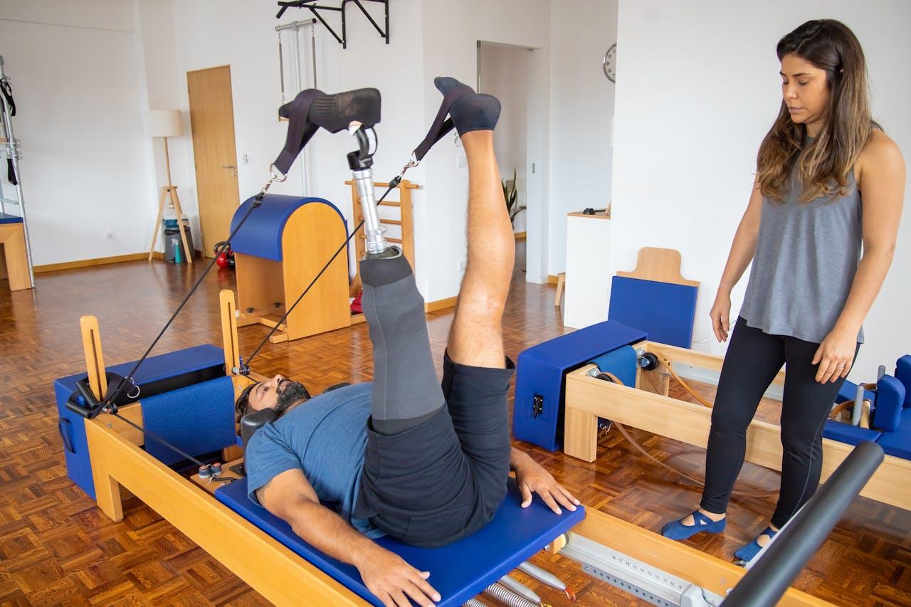 A person with a prosthetic leg using a Pilates Reformer