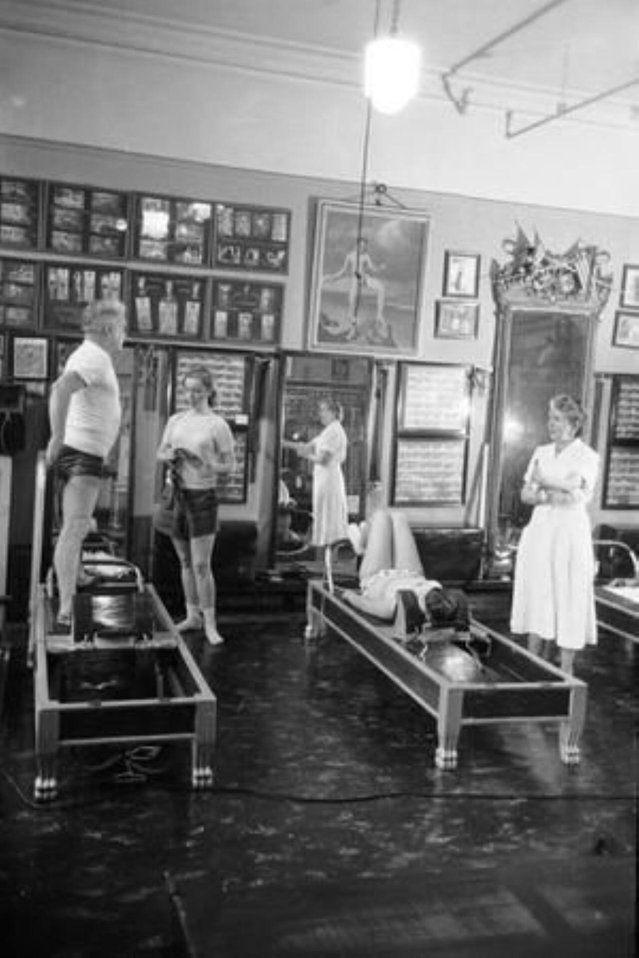 Black and white photo of individuals exercising in a gym, showcasing various fitness activities and equipment.