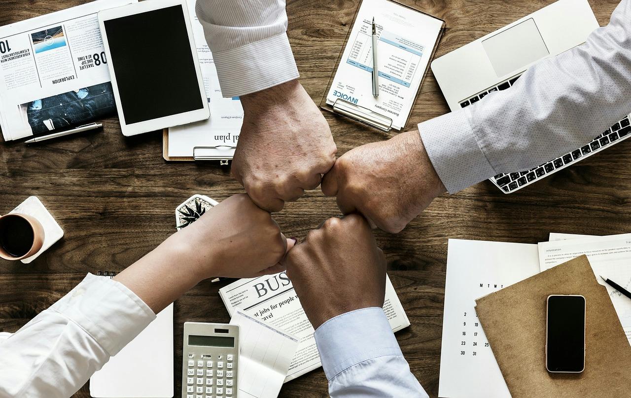 four people bumping hands over a table