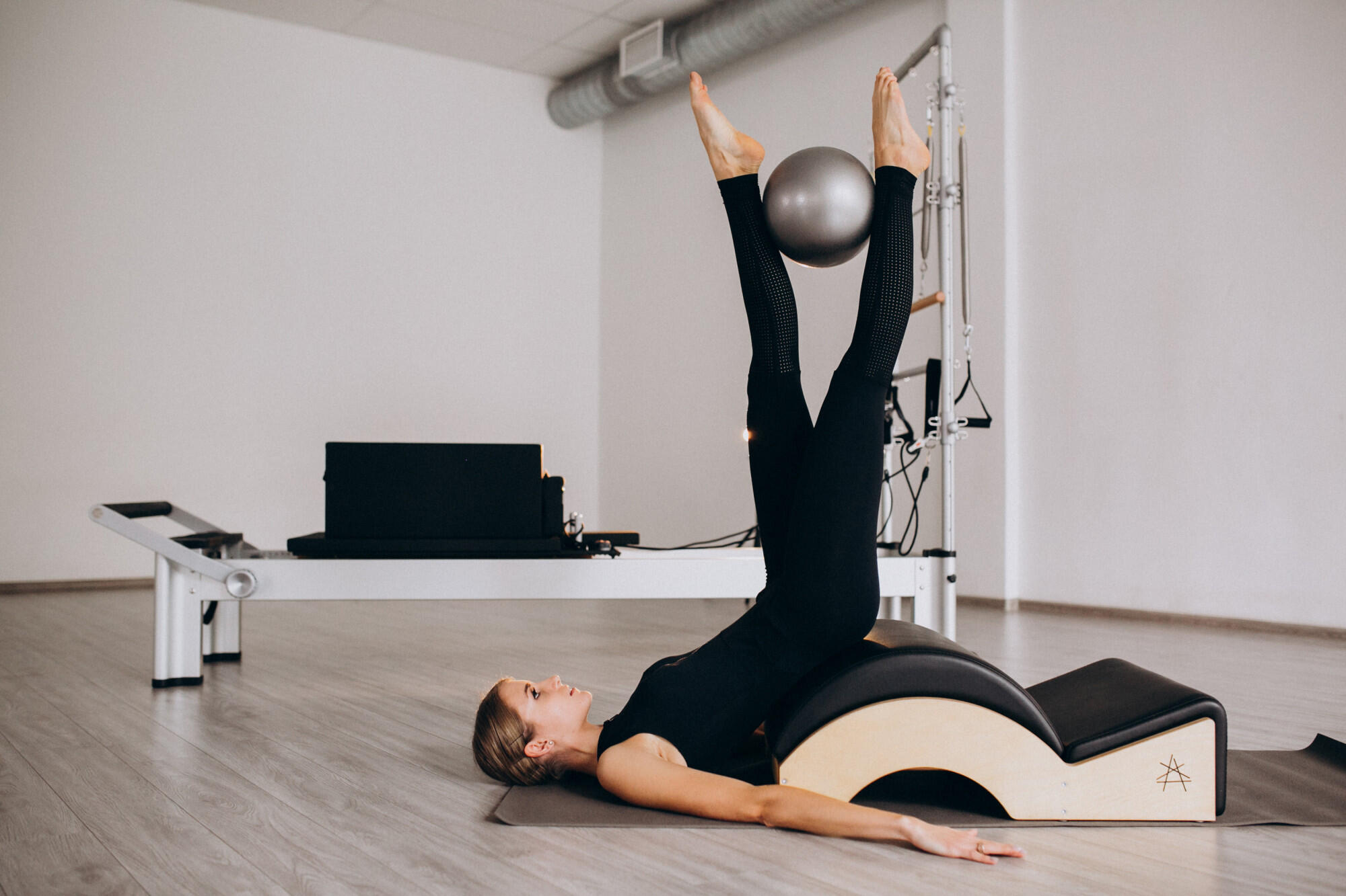 A woman performing a pilates exercise on a chair, focusing on balance and core strength.