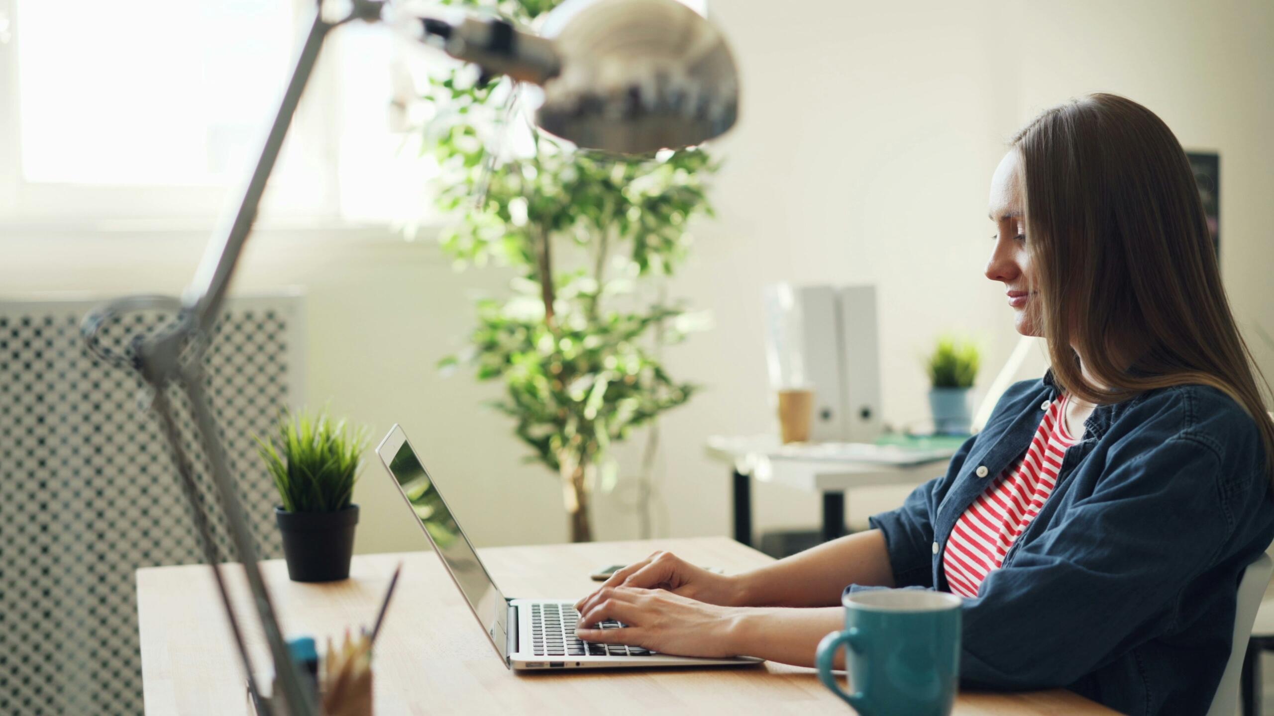 Smiling worker looking at a laptop on a desk.