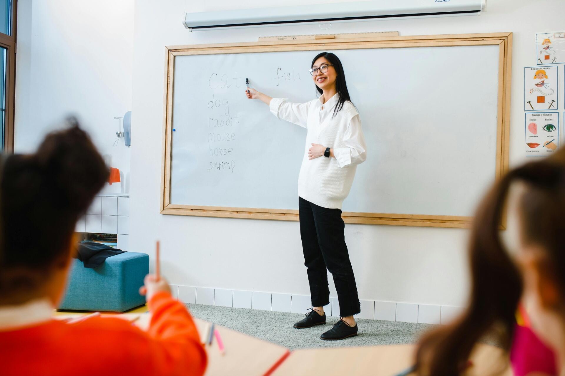 French teacher explaining vocabulary to students in a classroom, supporting structured language learning and classroom interaction.