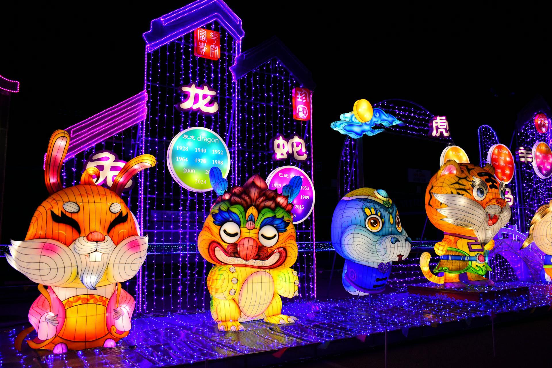 Vibrant Chinese lantern display featuring zodiac animals like a rabbit, tiger, and others, glowing in vivid colors against a dark night backdrop.