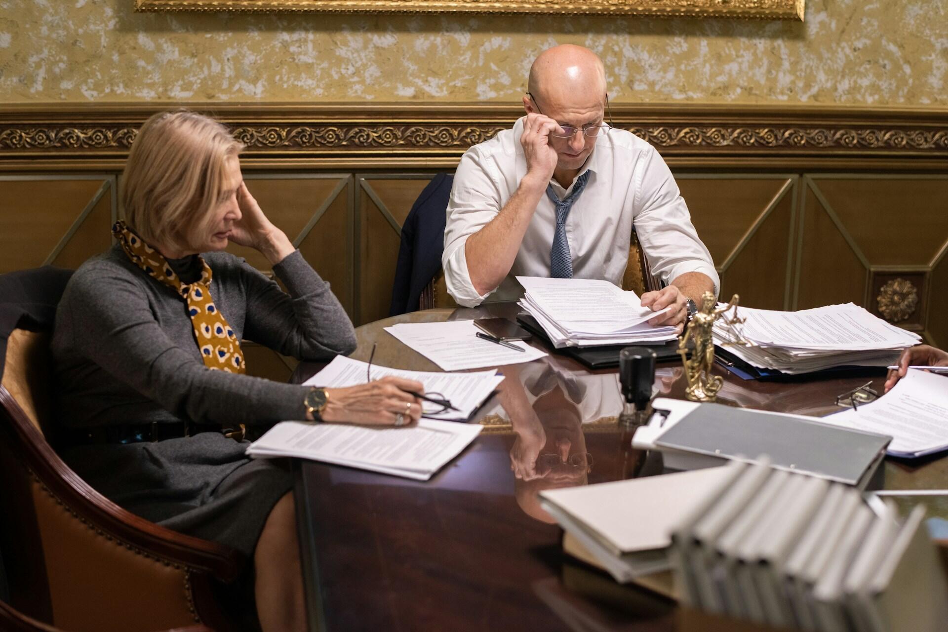 Two people at a table with papers in front of them.