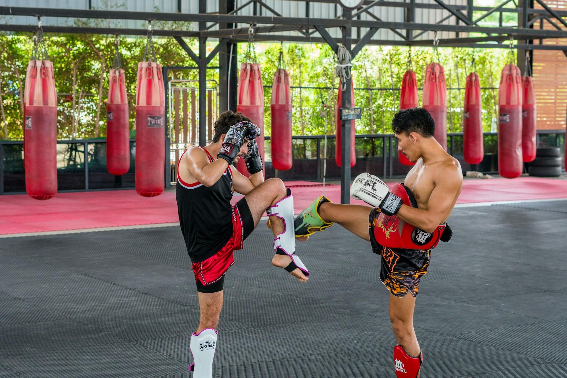 Inside a gym, two men dressed in black and red are fighting, demonstrating their strength and technique.