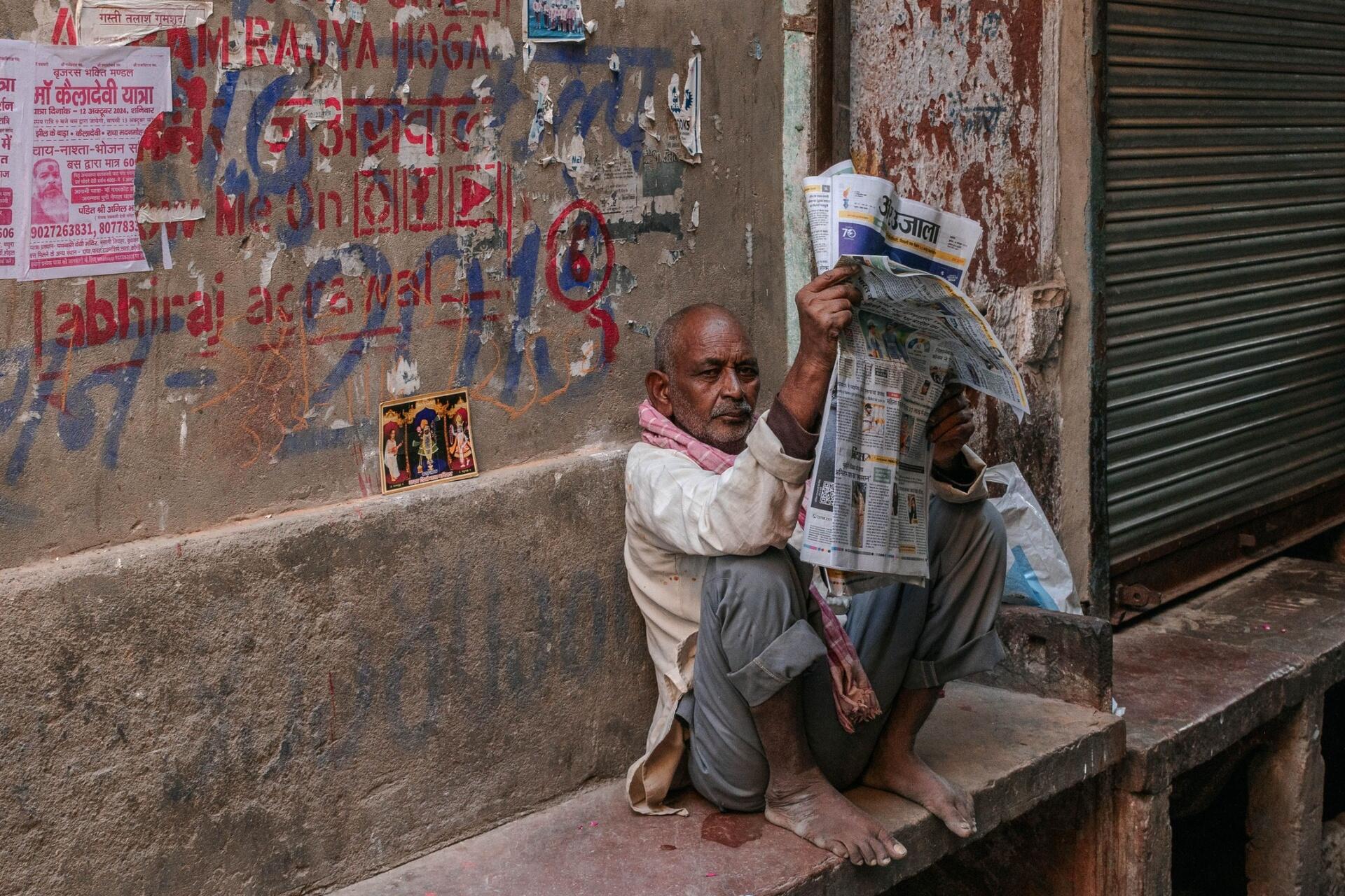 Man reading a Hindi newspaper on a street, illustrating real-world use of the Hindi language and authentic reading practice.