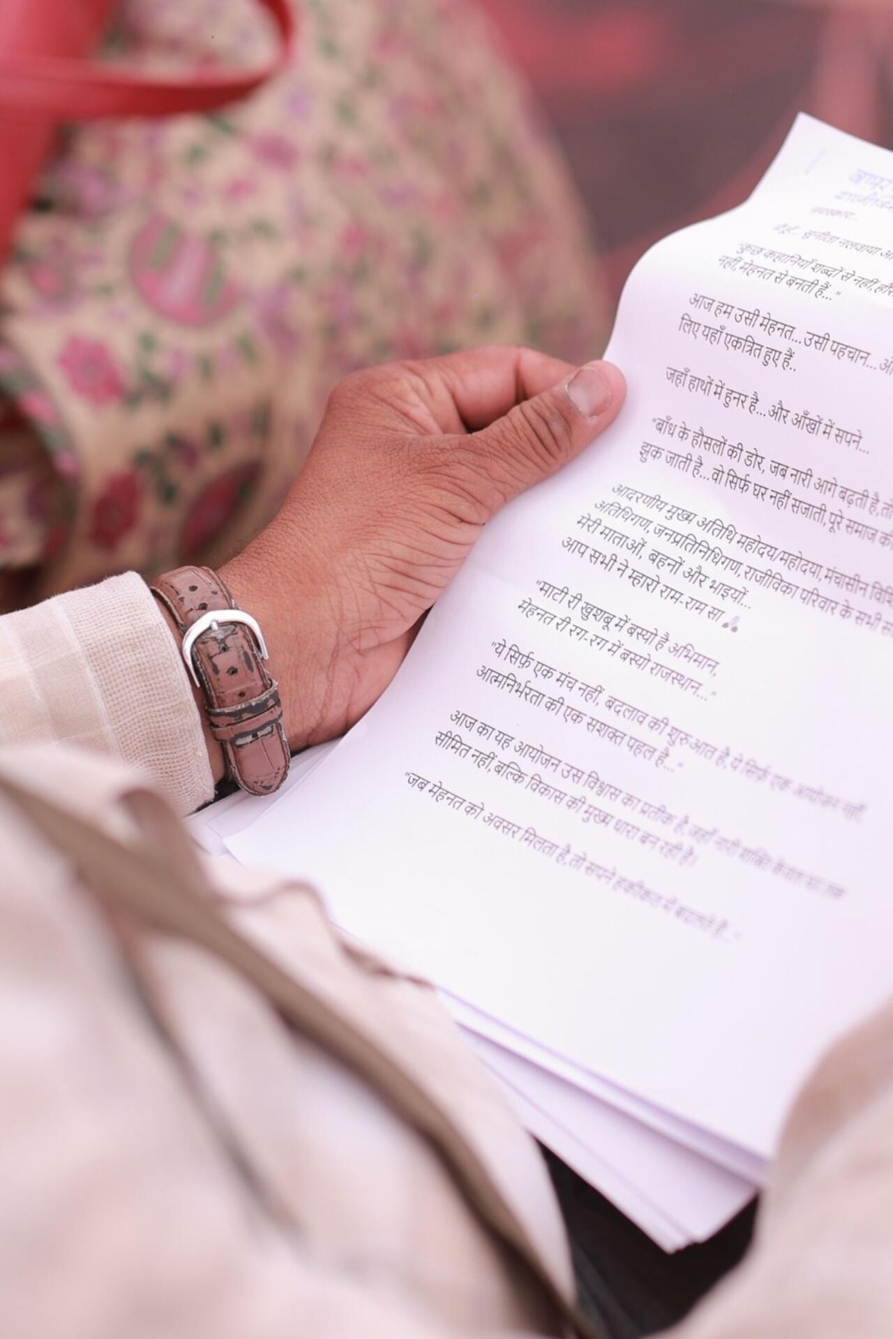 A person reading a Hindi text document closely, focusing on written sentences and language structure.