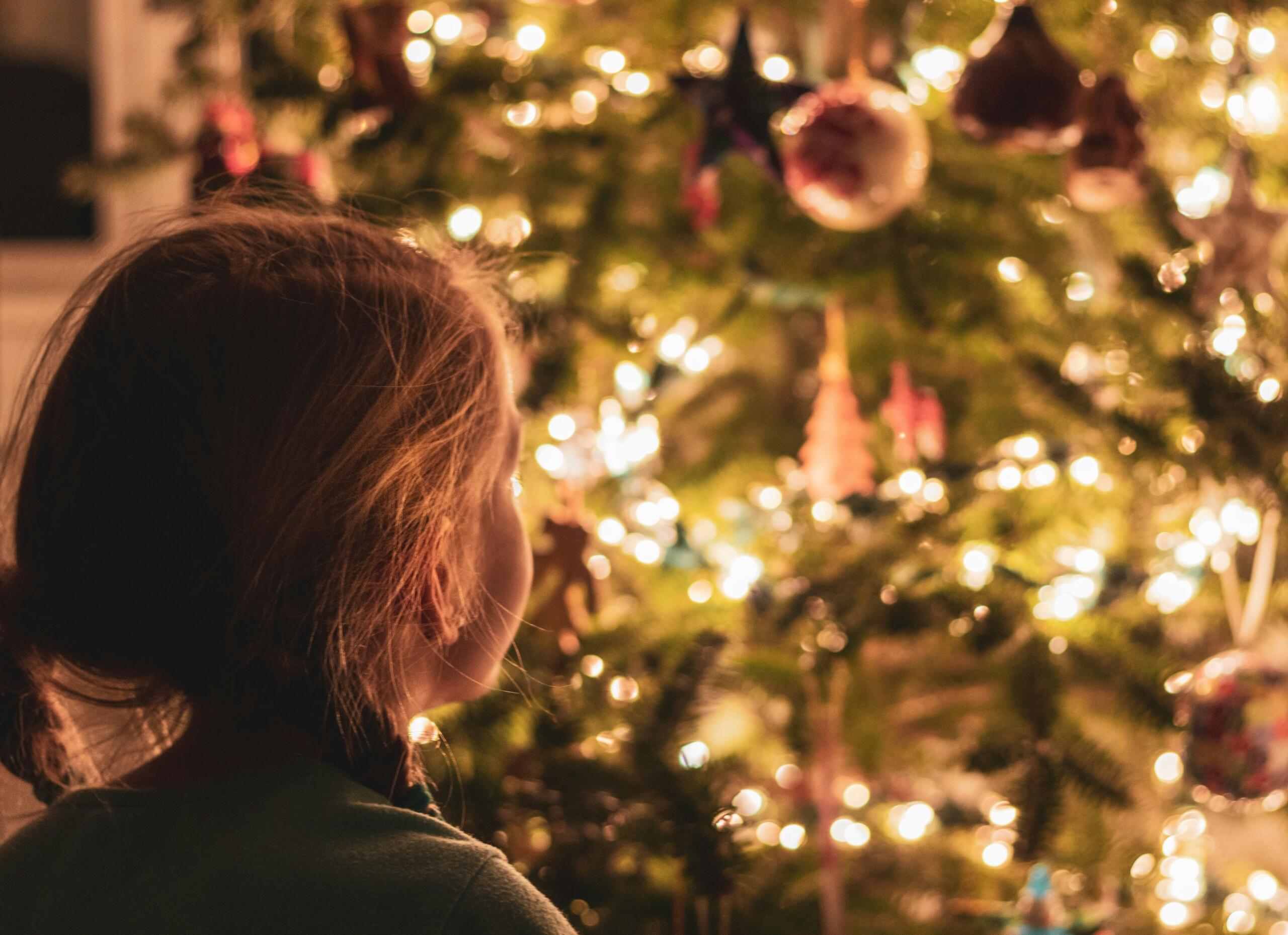 A girl looking at a Christmas tree.