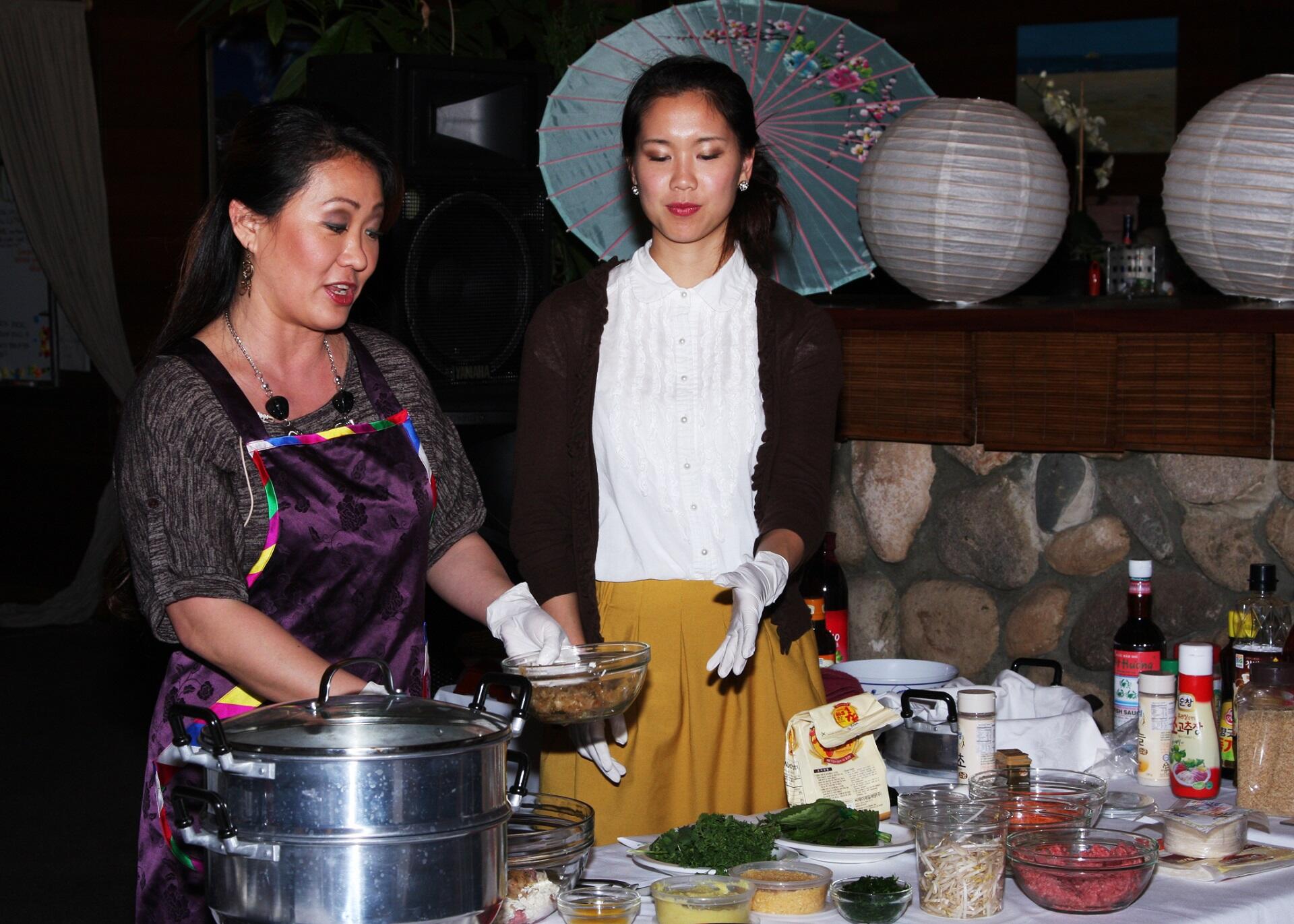 Two women preparing food in a public kitchen.