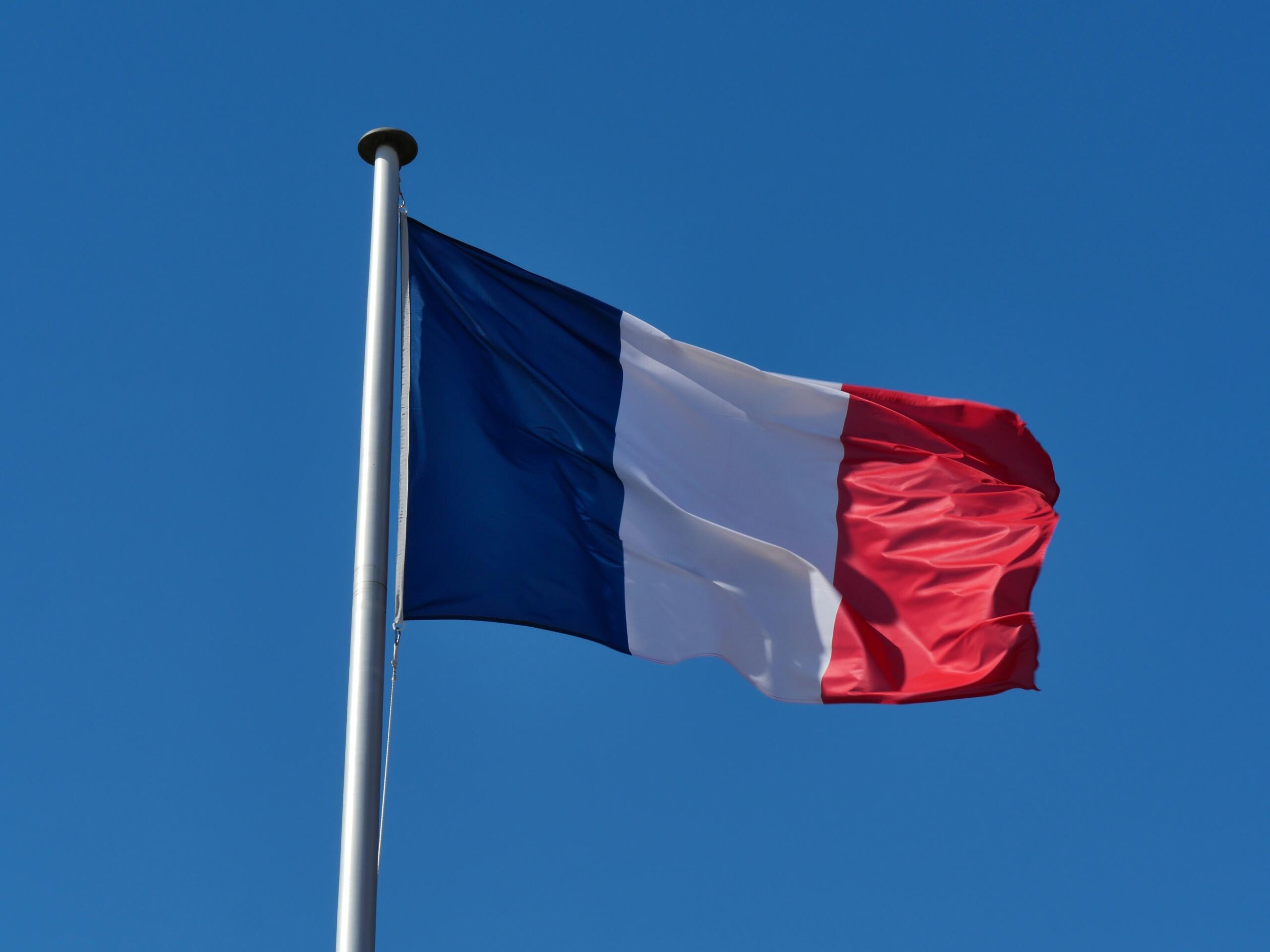 The French flag set against a blye sky.