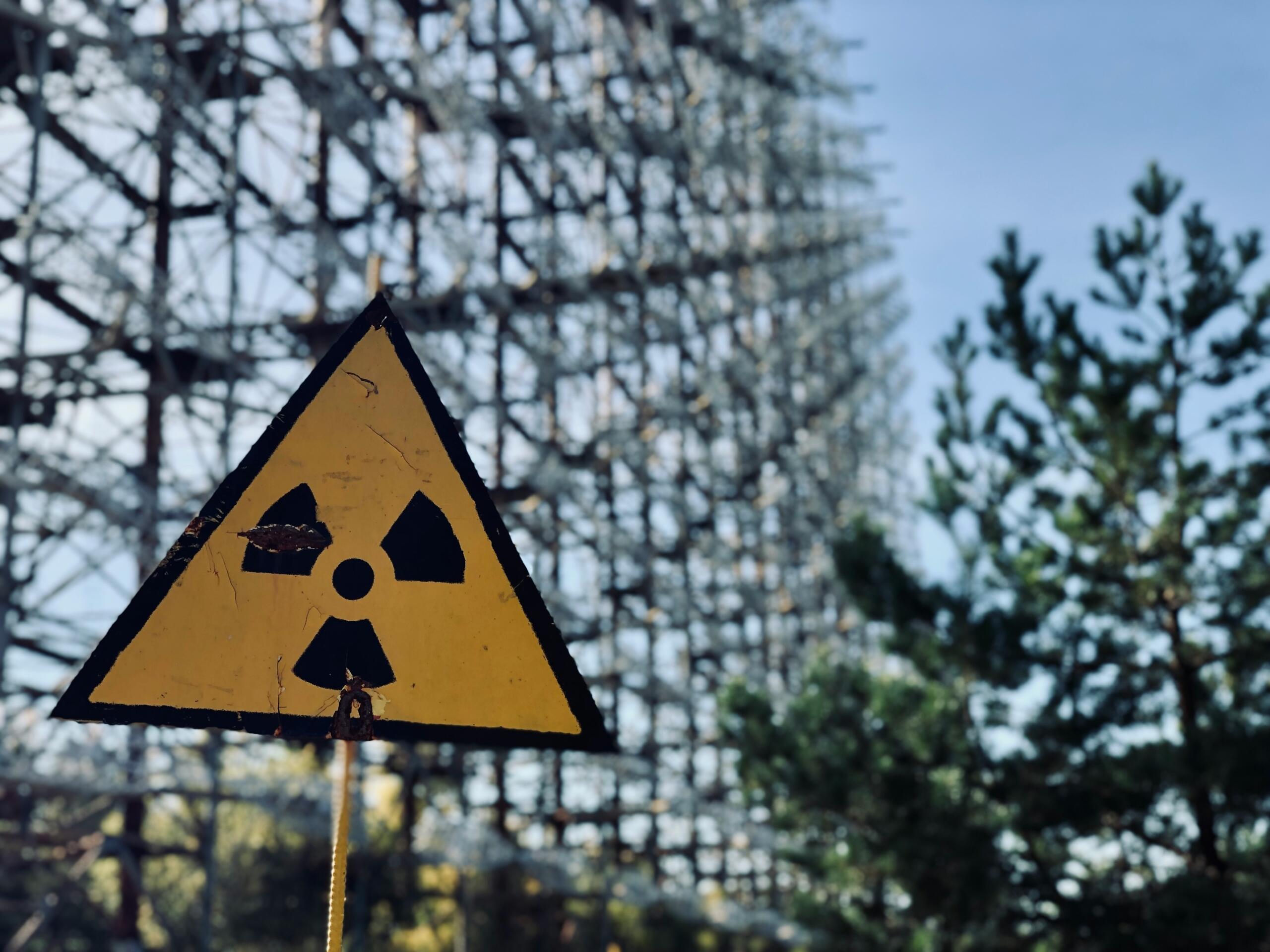 A radioactive warning sign displayed prominently in front of a large industrial structure.