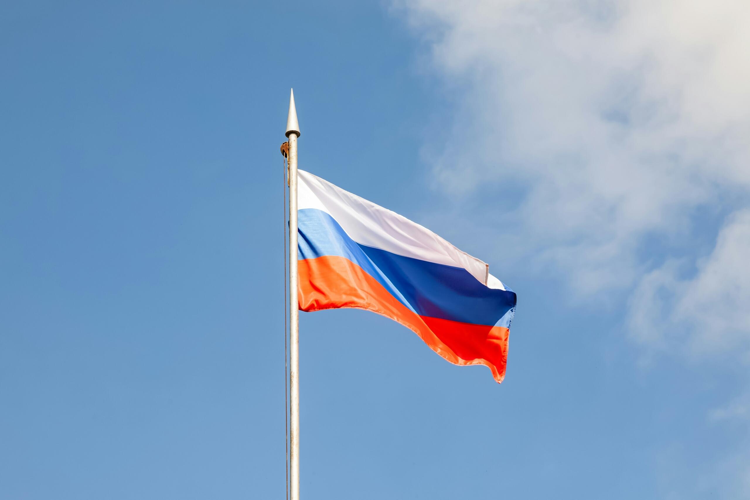 The Russian flag set against a blue sky.