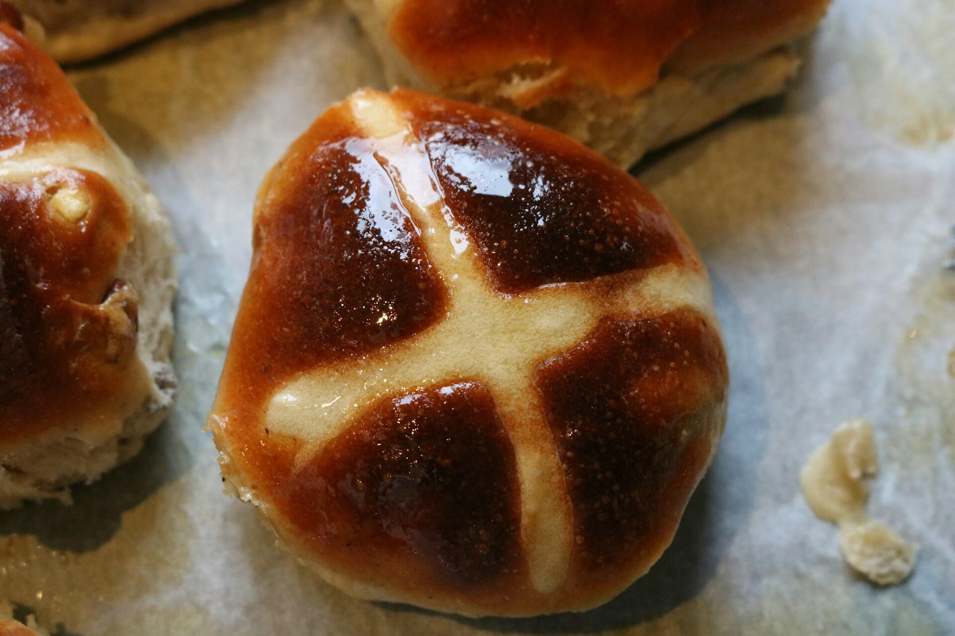 Freshly baked rolls with a golden-brown crust arranged on a baking sheet lined with parchment paper.