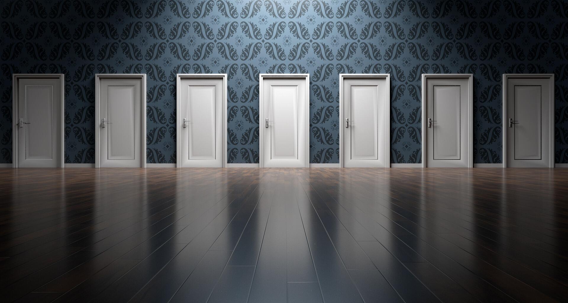 A corridor with six white doors