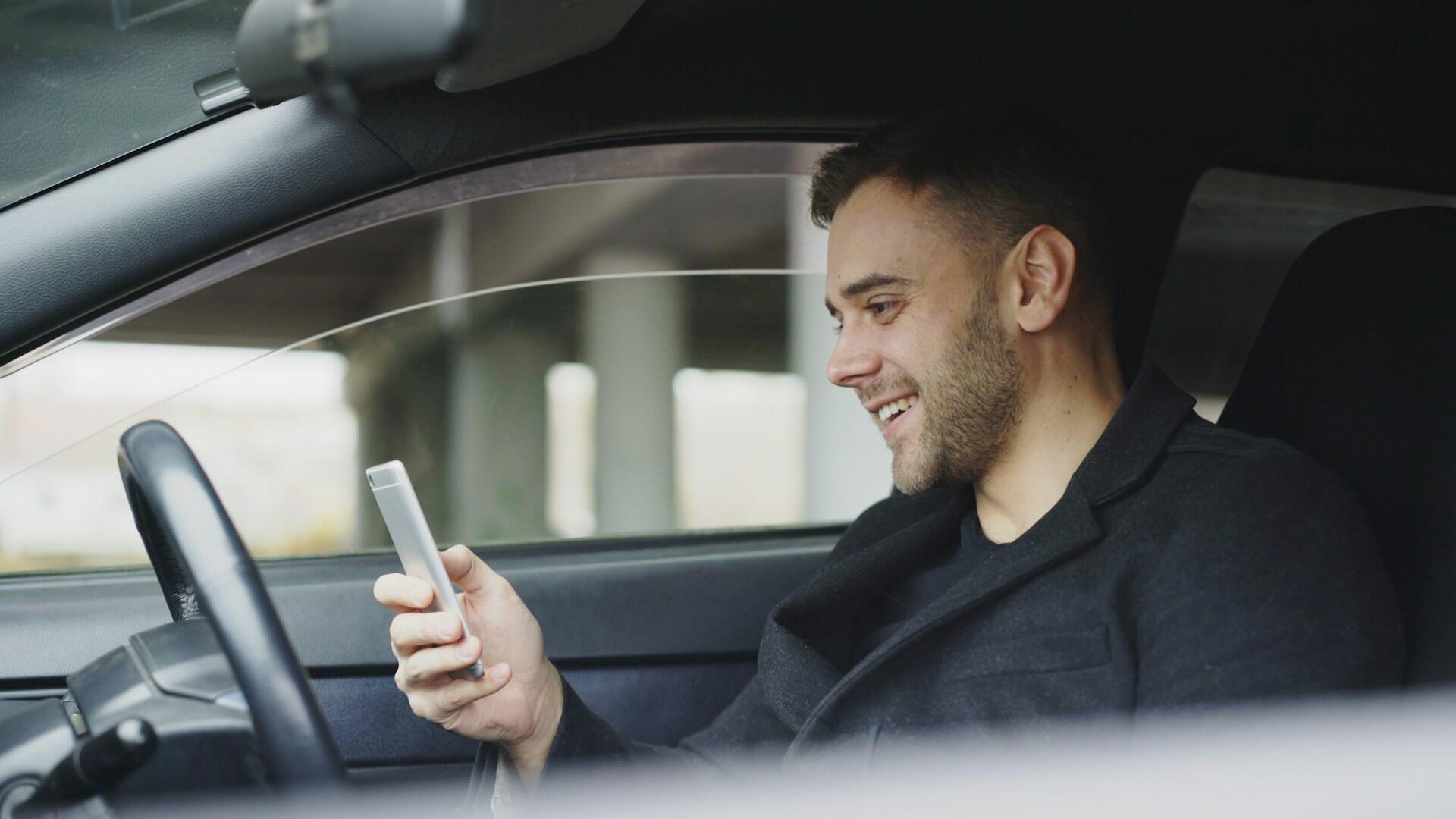A person holds a phone in one hand while driving. 