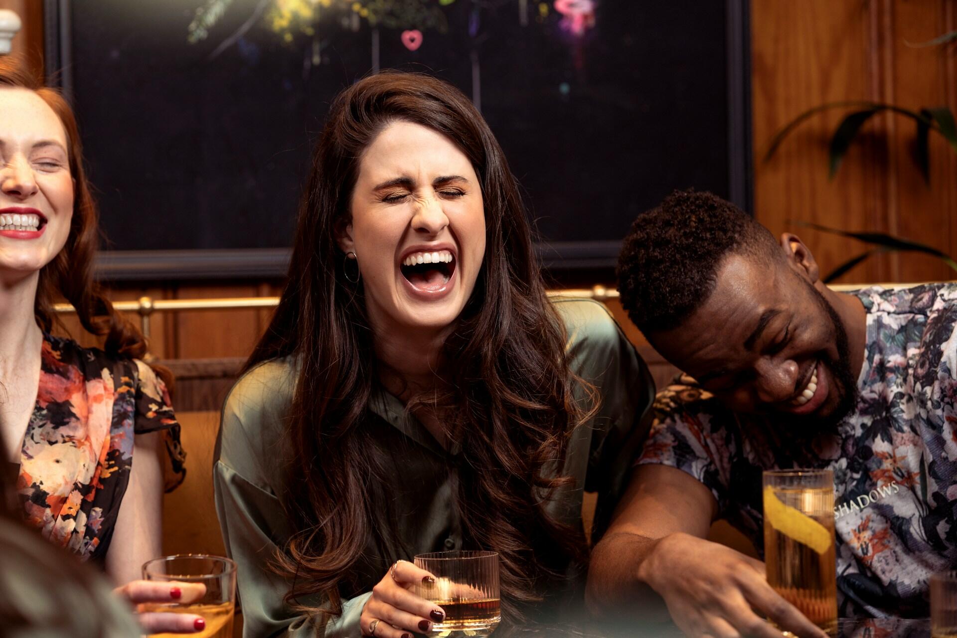 Three people laughing while sititng close together.