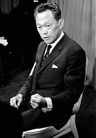 A black-and-white photo of Lee Kuan Yew, seated in a chair during an interview.