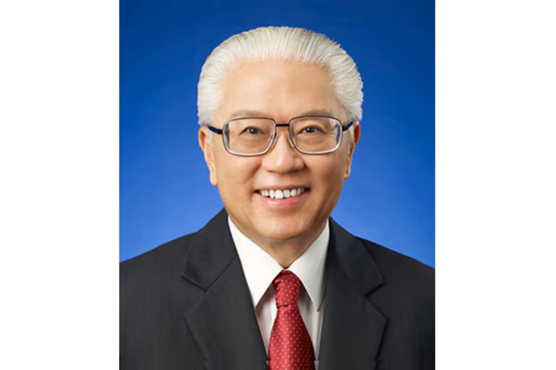 Portrait of Tony Tan wearing a black suit, white shirt, and red tie against a blue background.