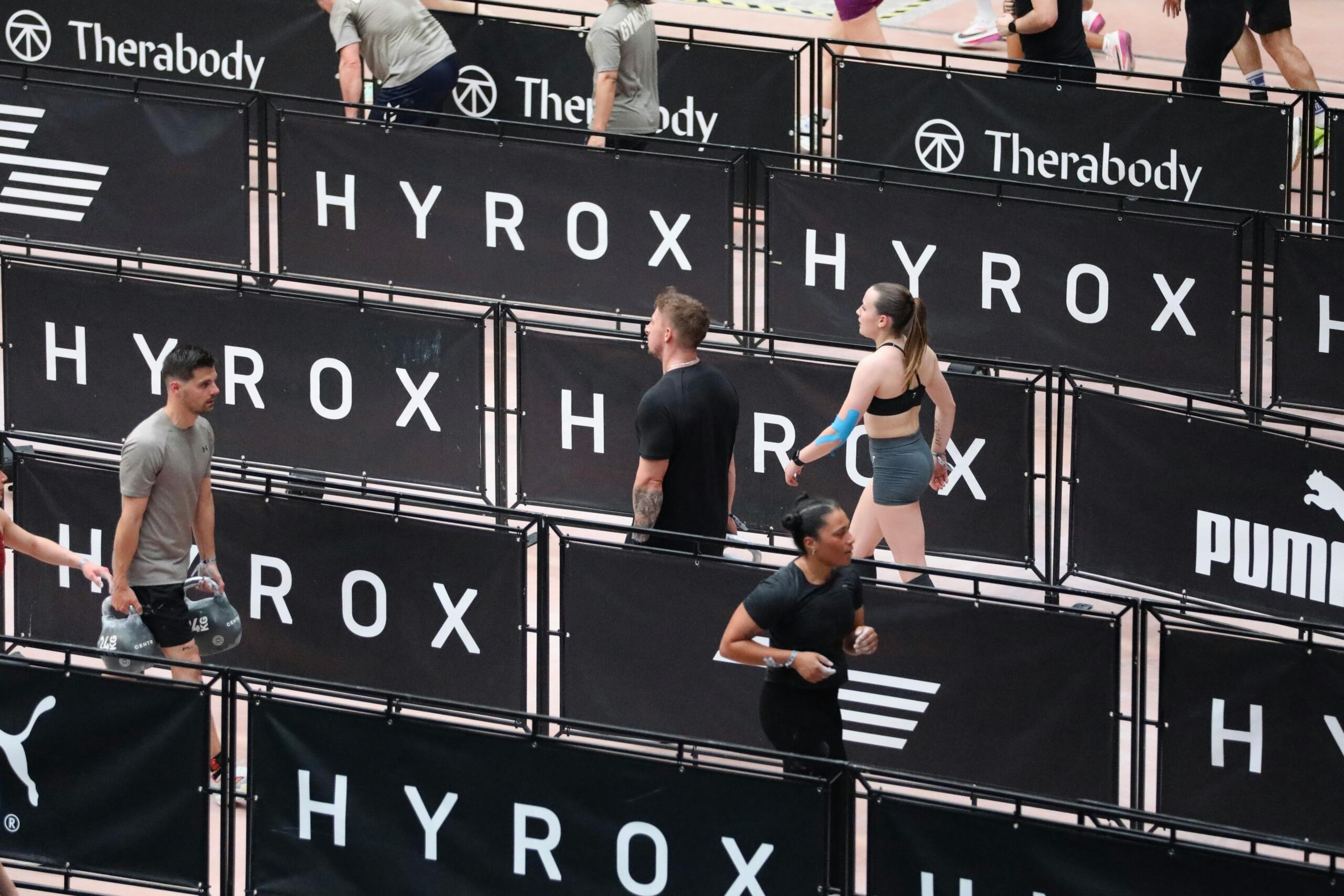 Athletes compete in a HYROX event featuring various sports brands.