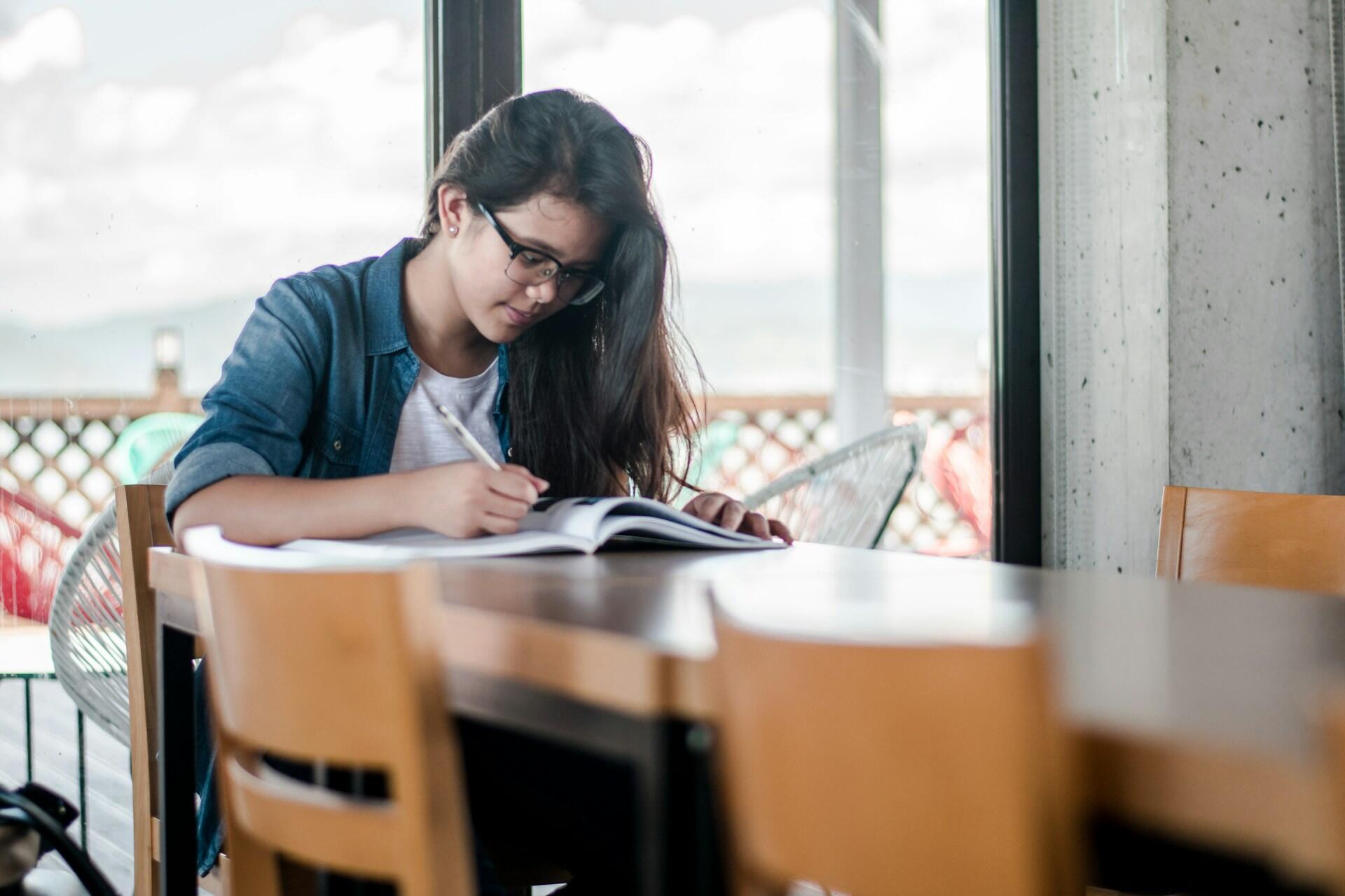 Student writing in a notebook at a table