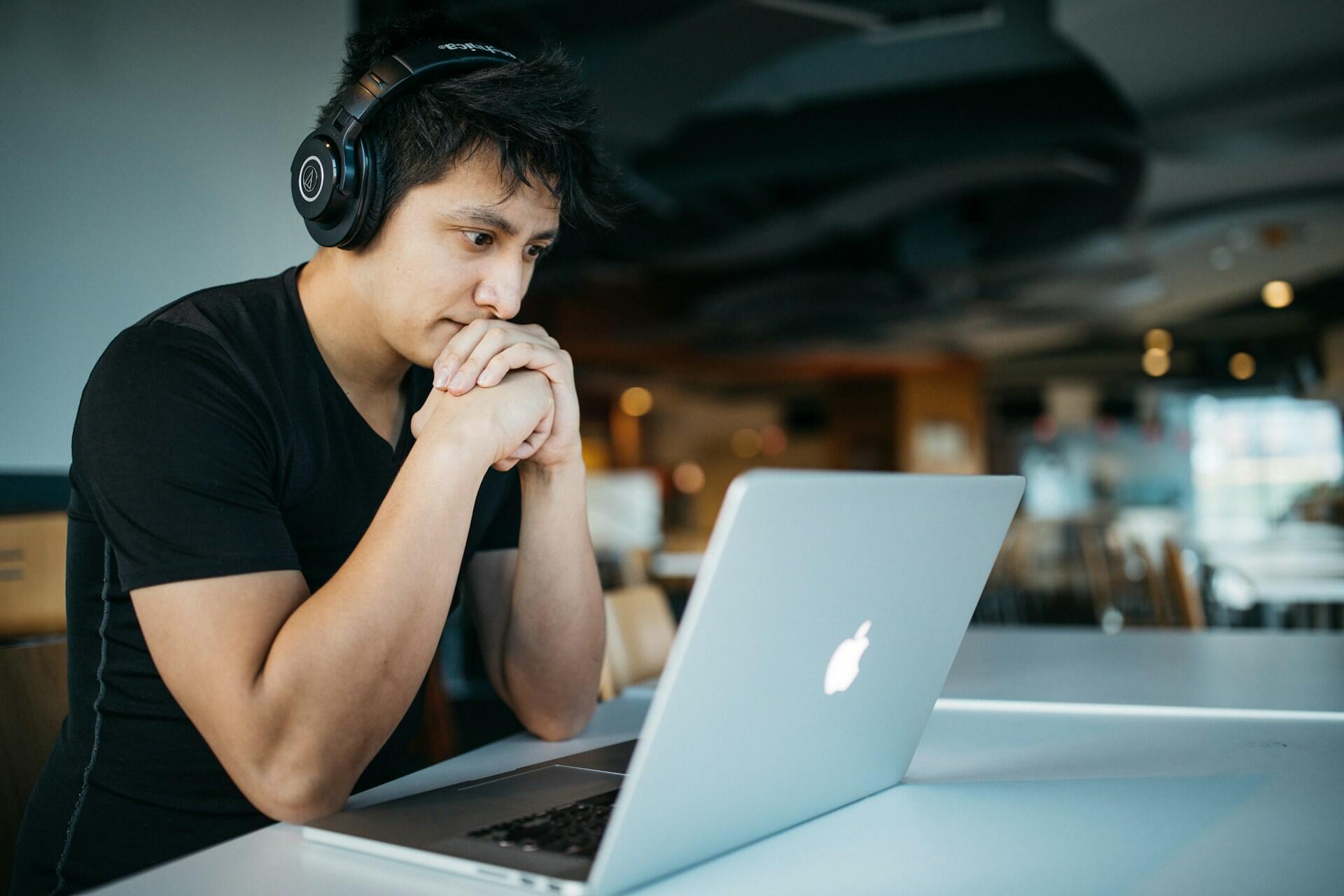 Person wearing headphones while looking at a laptop