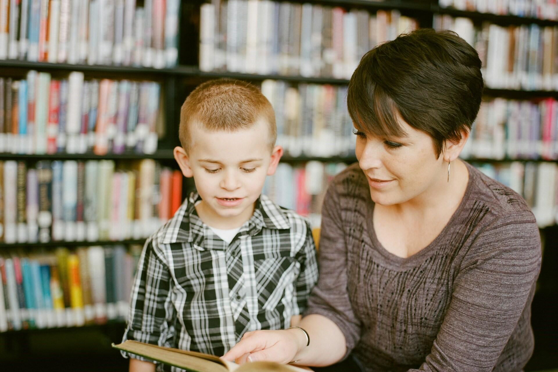 Adult and child reading a book in a library