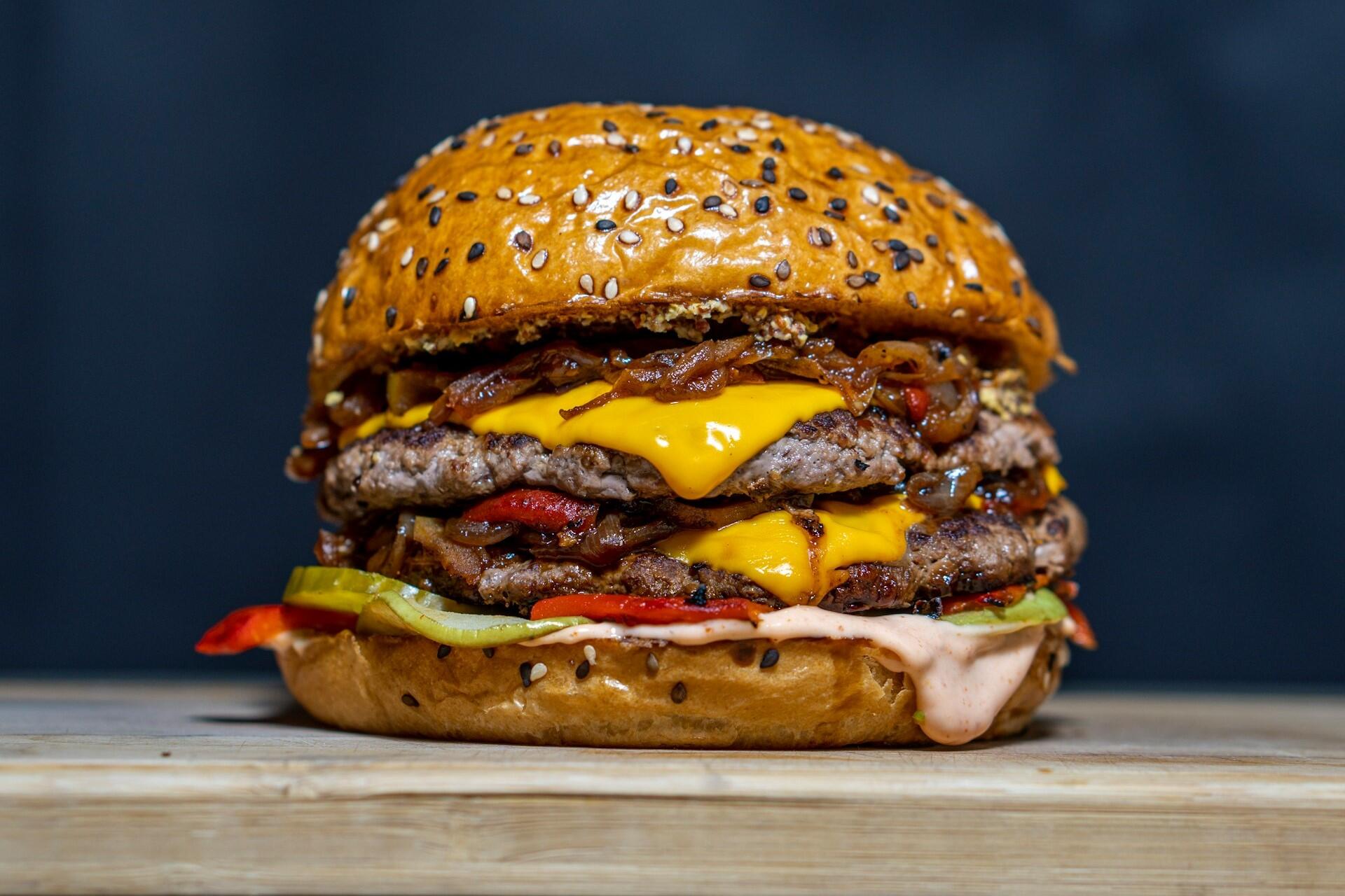 Cheeseburger with sesame bun on a wooden surface